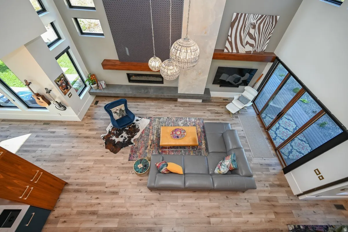 Spacious living area featuring high ceilings, light wood-finish flooring, and a linear fireplace with a concrete-style hearth