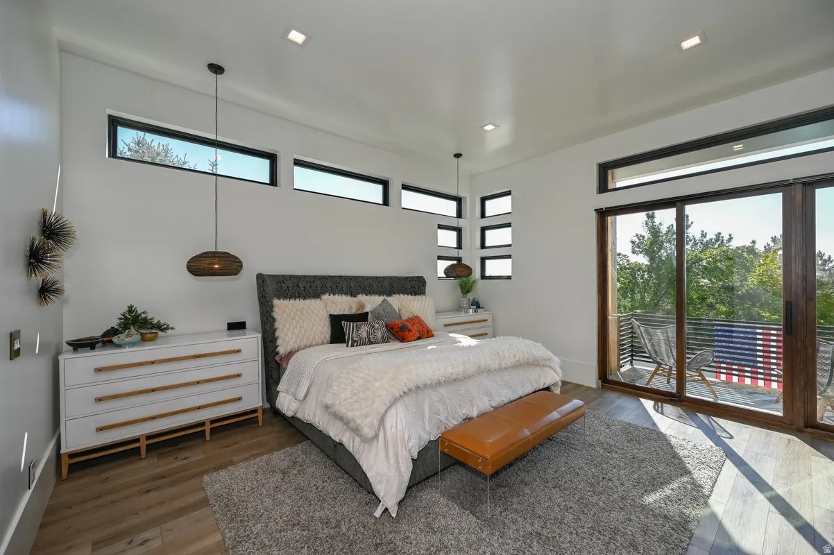 Bedroom featuring wood-finish flooring, recessed lighting, and a private balcony with a metal railing system