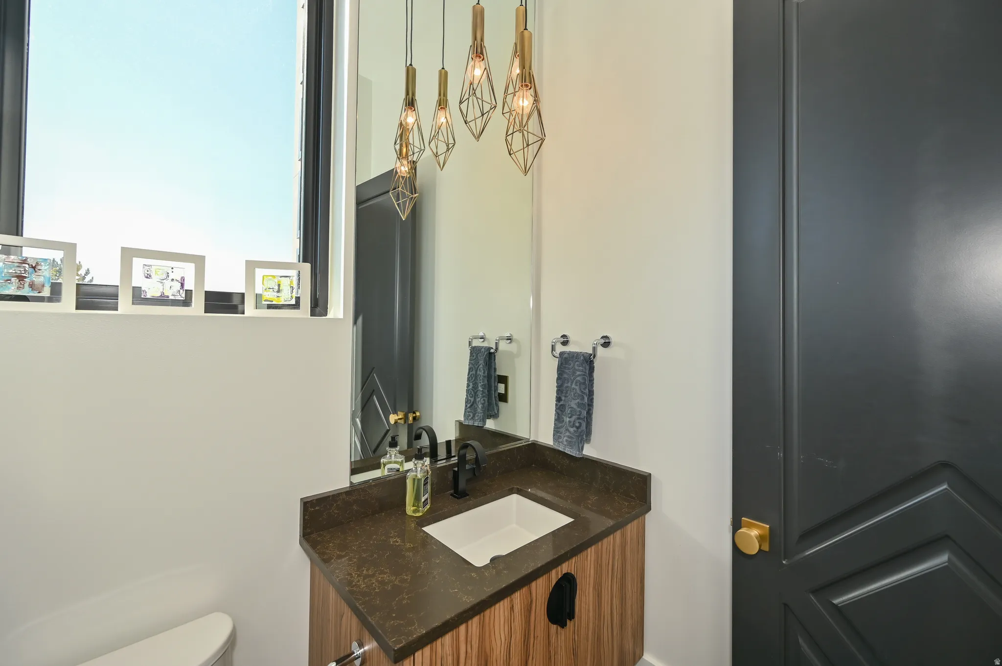Modern vanity featuring a rectangular undermount sink, dark countertop, and matte black faucet
