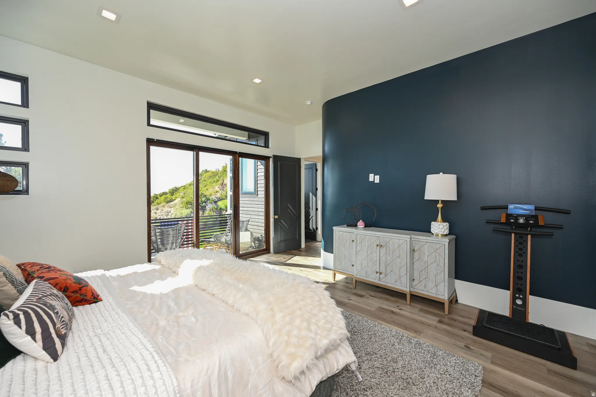 Spacious room featuring wood-finish flooring, a contemporary accent wall, and recessed ceiling lights