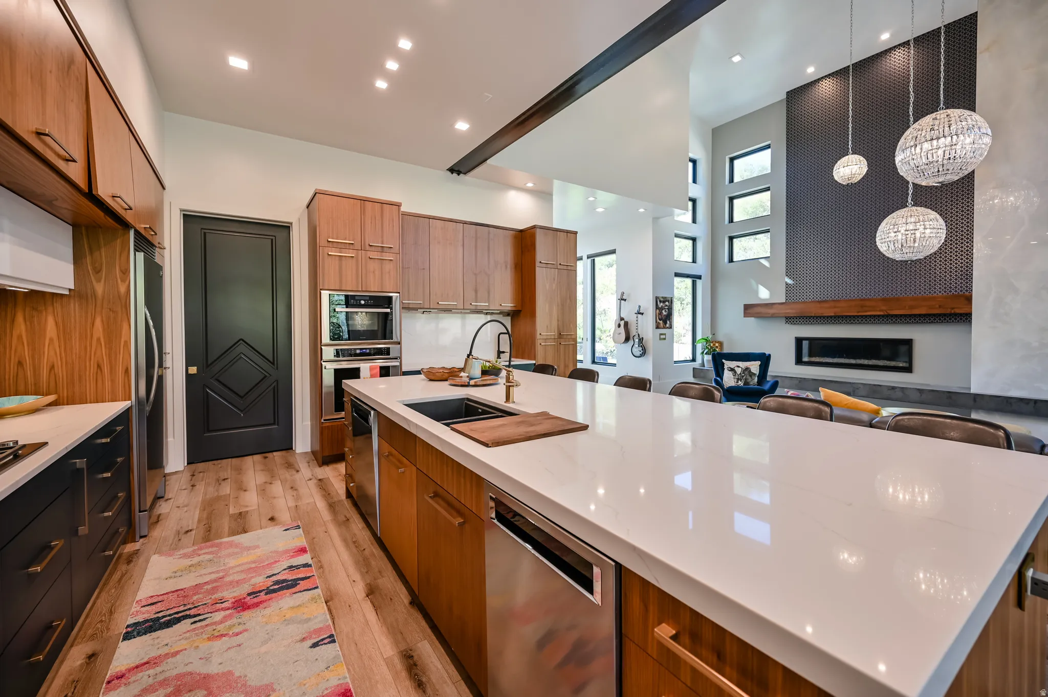 Gourmet kitchen featuring a large island with white stone countertop, built-in stainless steel appliances, wood-finish cabinetry, and wood-finish flooring