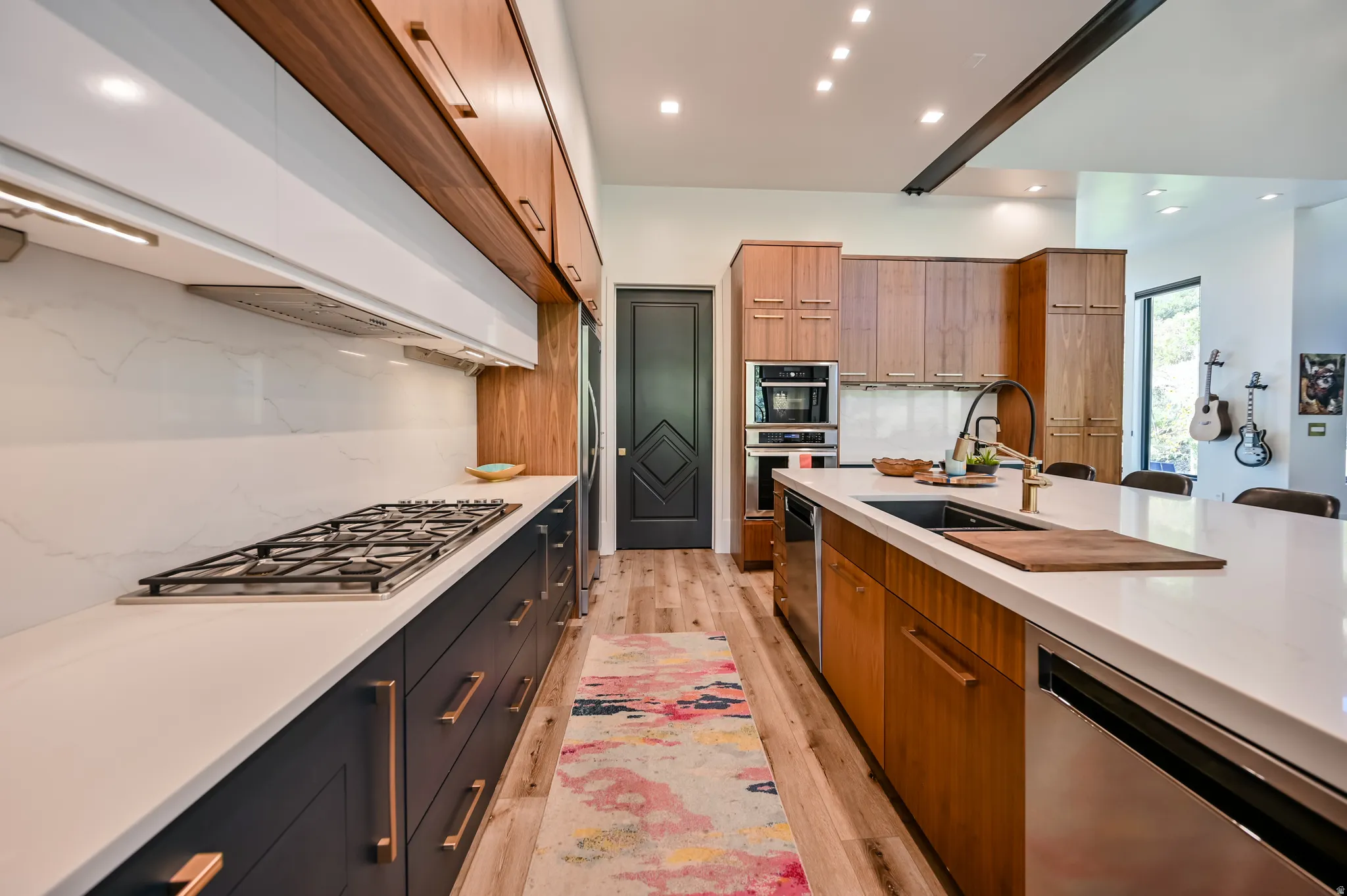 Contemporary kitchen featuring an integrated gas cooktop, sleek white countertops, and a blend of dark cabinetry with wood-finish upper cabinets