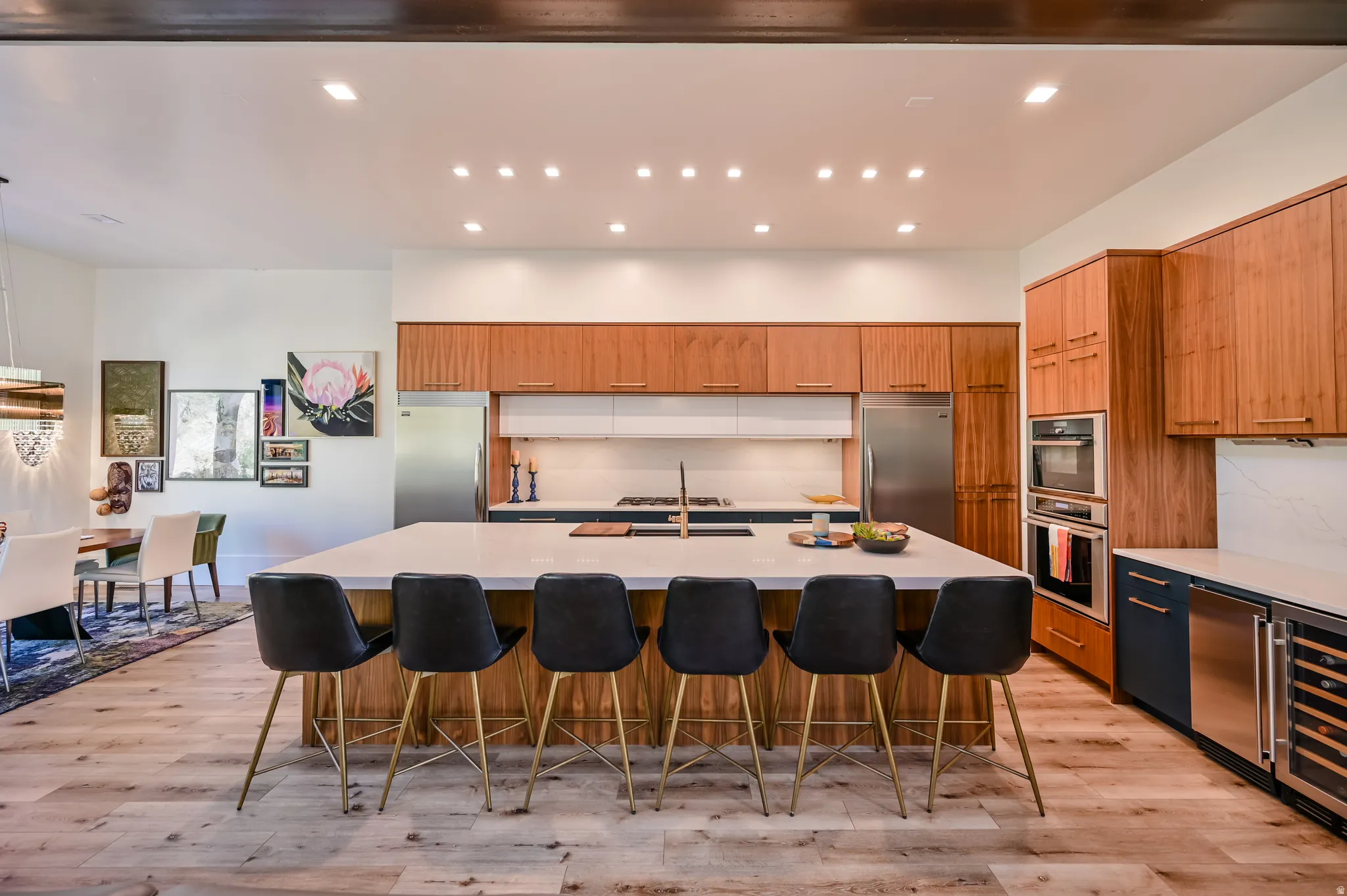 Gourmet kitchen featuring a large central island, light wood-finish flooring, integrated stainless steel appliances, abundant cabinetry, and recessed lighting
