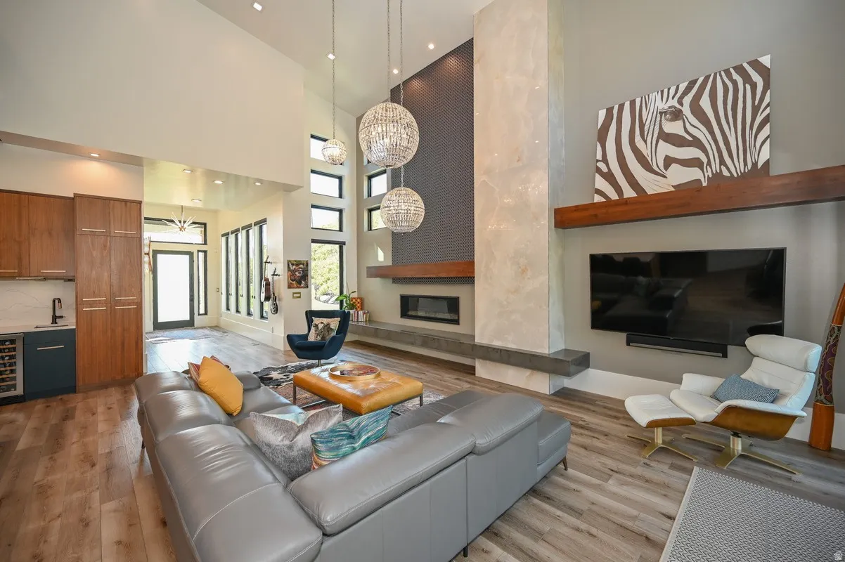 Spacious living area featuring high ceilings, wood-finish flooring, and a contemporary fireplace with a stone surround
