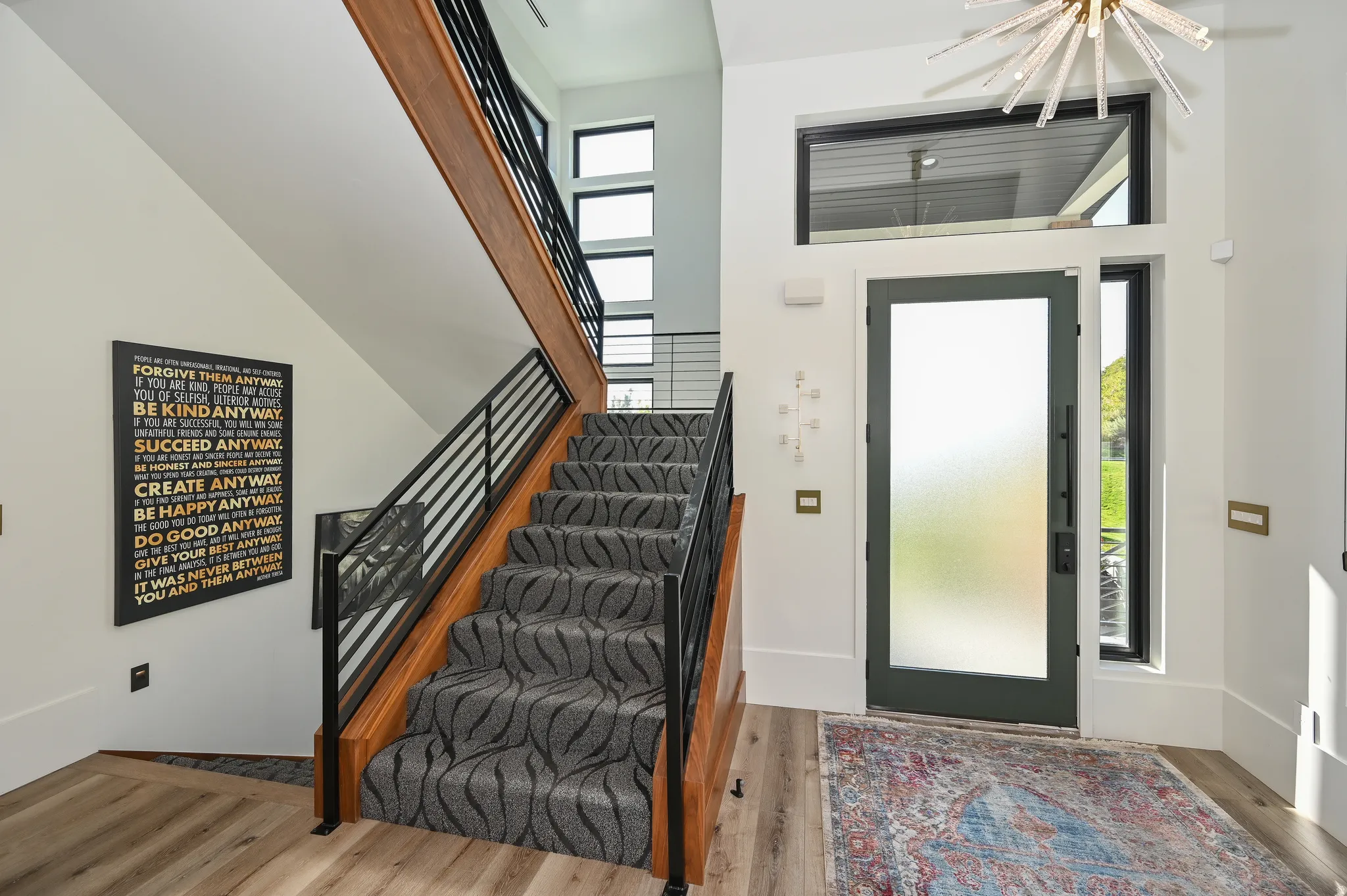 Modern staircase featuring wood treads, black metal railings, and patterned carpet