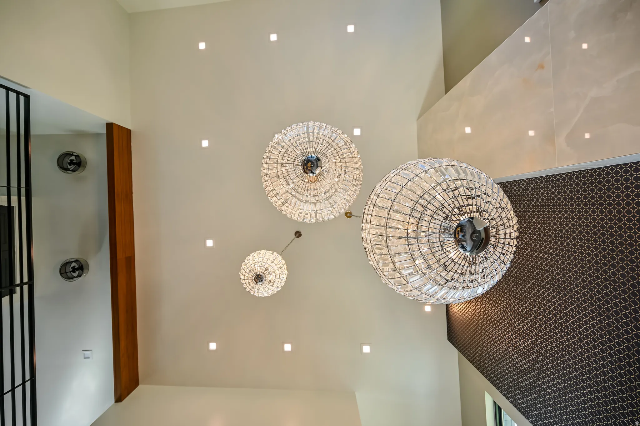 Dramatic high ceiling featuring three crystal chandeliers and recessed lighting
