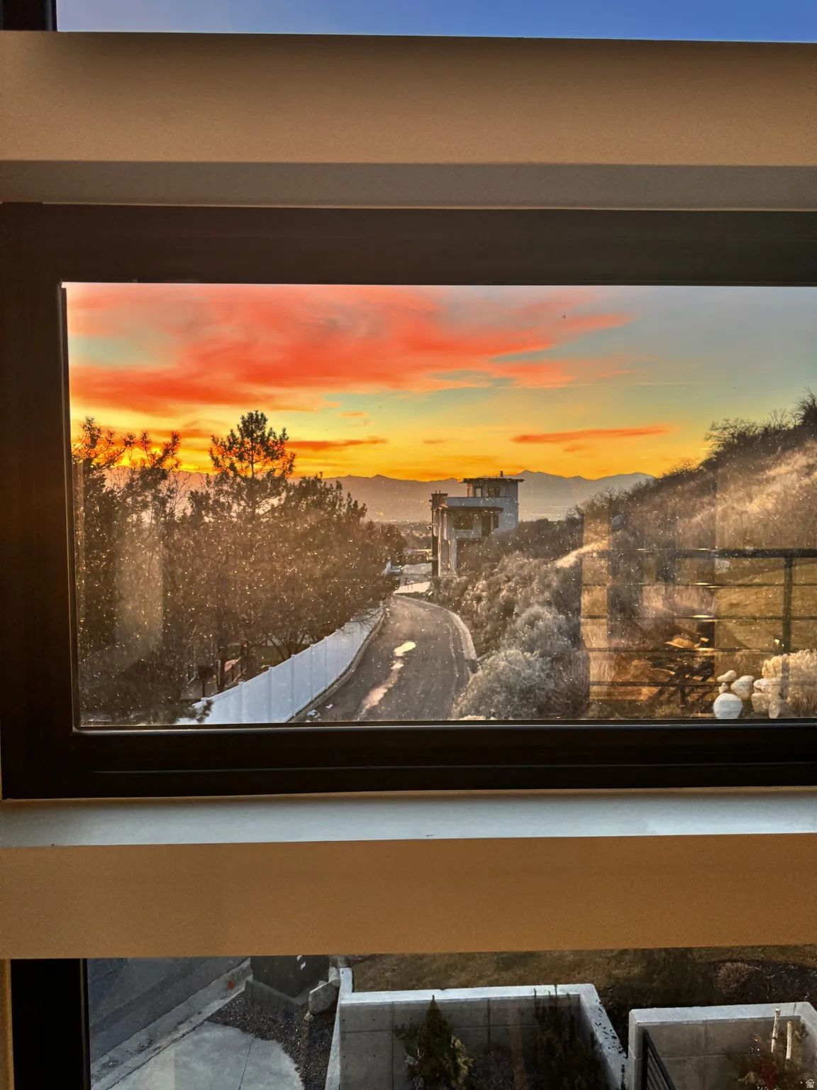 Framed window showcasing a vibrant sunset over distant mountains