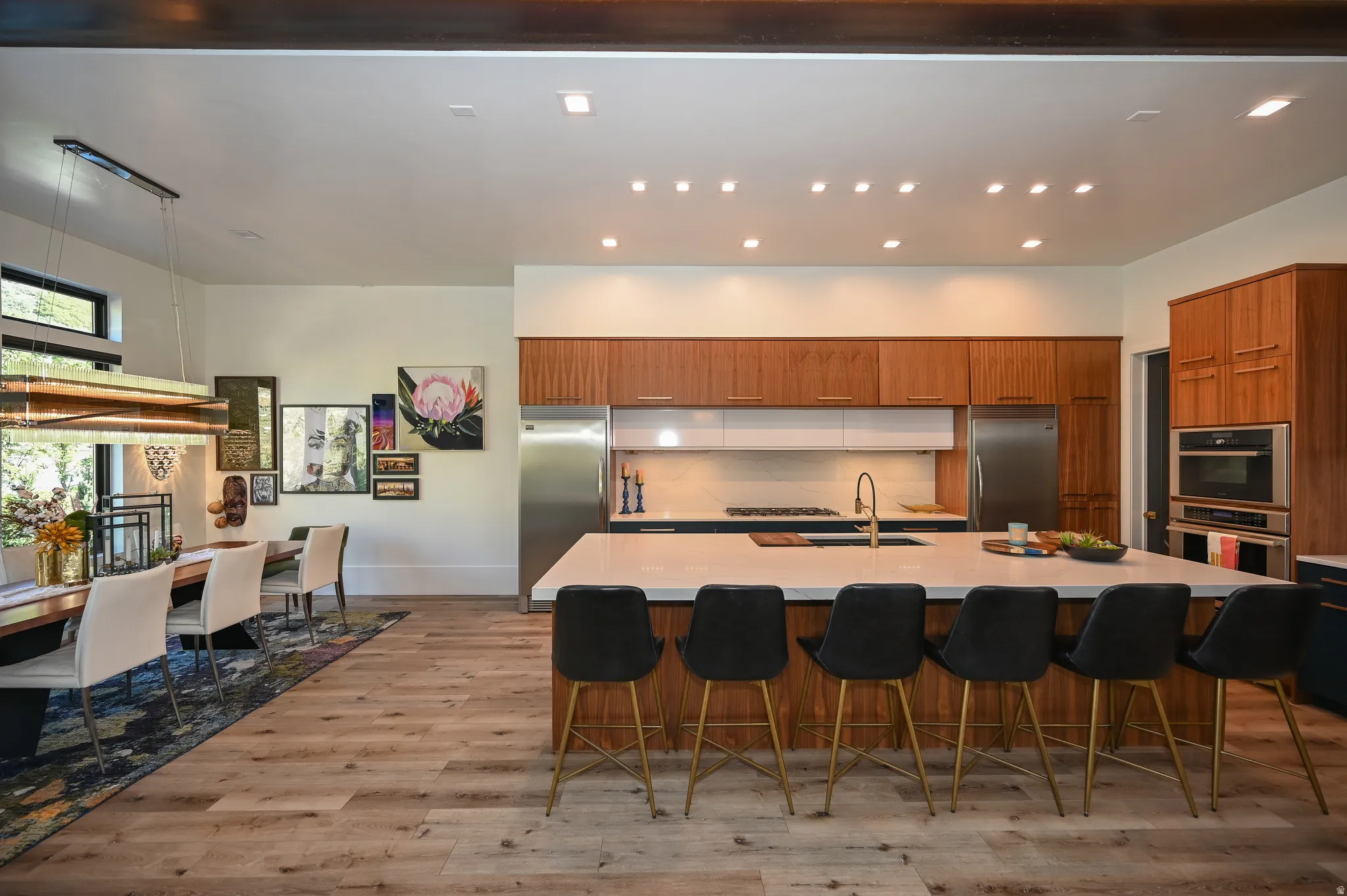 Contemporary kitchen featuring a large center island with seating, integrated appliances, wood-finish cabinetry, and recessed lighting