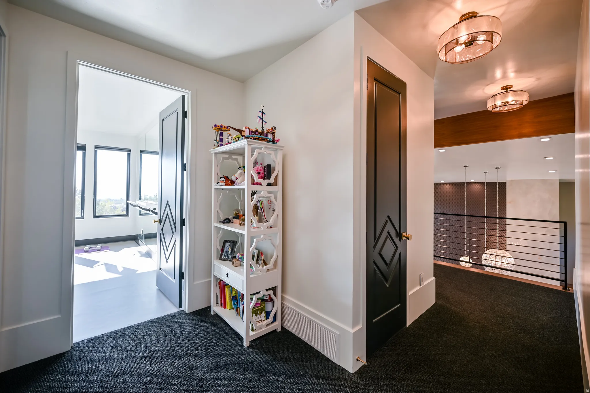 Hallway featuring dark carpet flooring, custom doors with diamond paneling, and two semi-flush mount ceiling lights