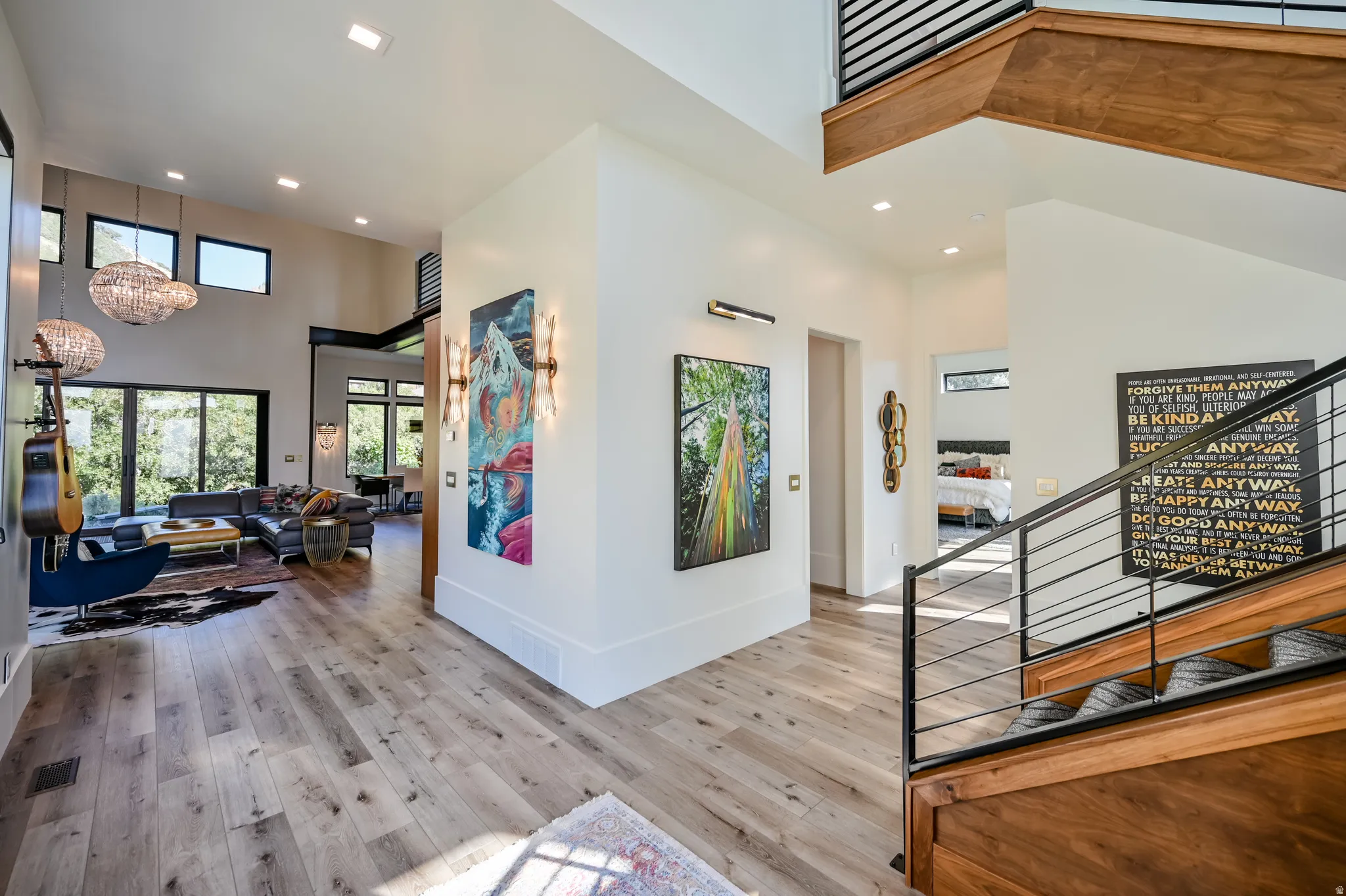 Spacious interior featuring wood-finish flooring, a contemporary staircase with wood treads and metal railings, and a living area with high ceilings and large windows