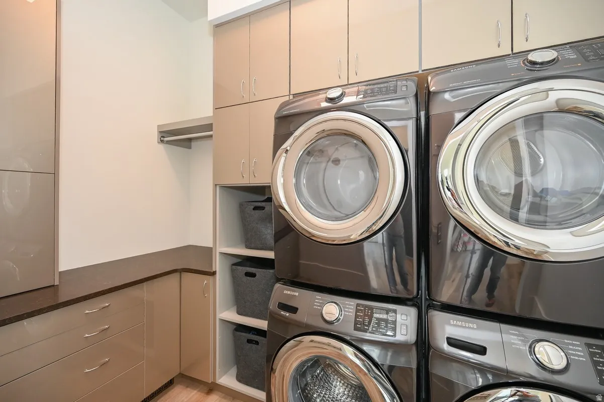 Dedicated laundry room featuring high-capacity front-load washer and dryer, extensive built-in cabinetry for storage, integrated countertops, and open shelving