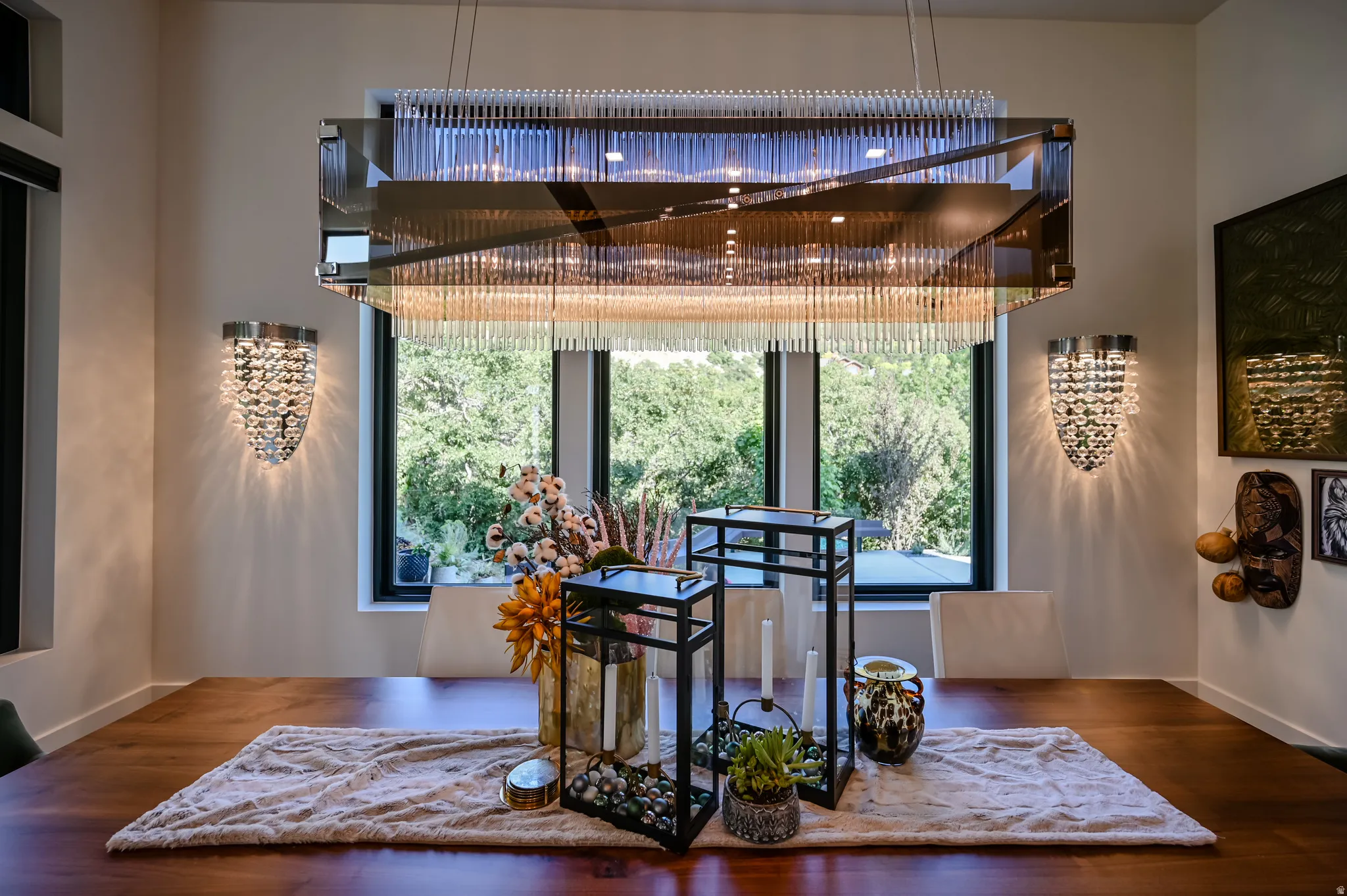 Formal dining area featuring a prominent rectangular chandelier with glass rods, recessed lighting, and dual crystal sconces