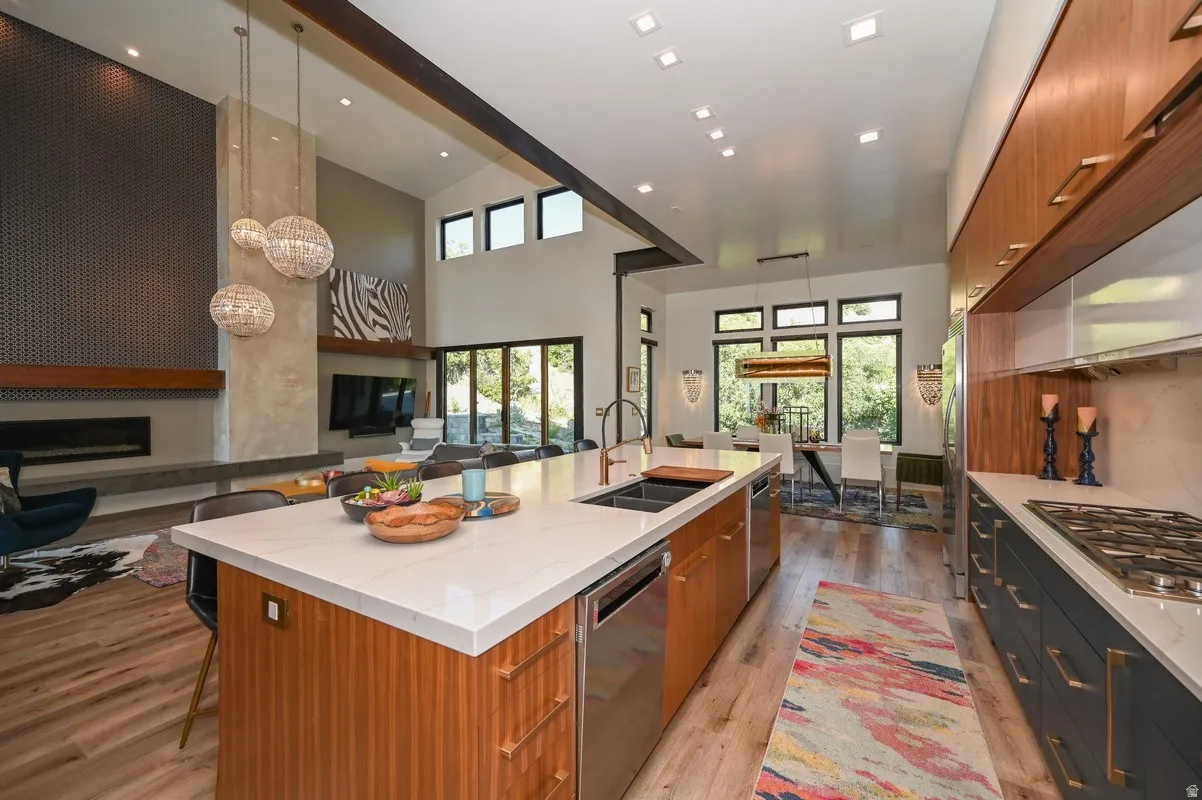 Open-concept kitchen featuring a large island with integrated sink, stainless steel appliances, and wood-finish flooring