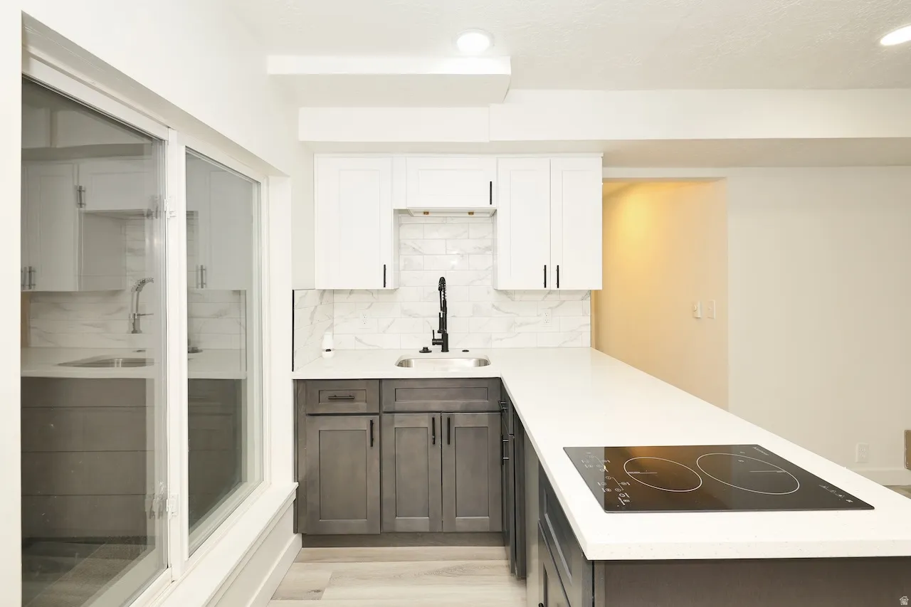 Modern kitchen featuring two-tone cabinetry with matte black hardware, white countertops, and a white subway tile backsplash