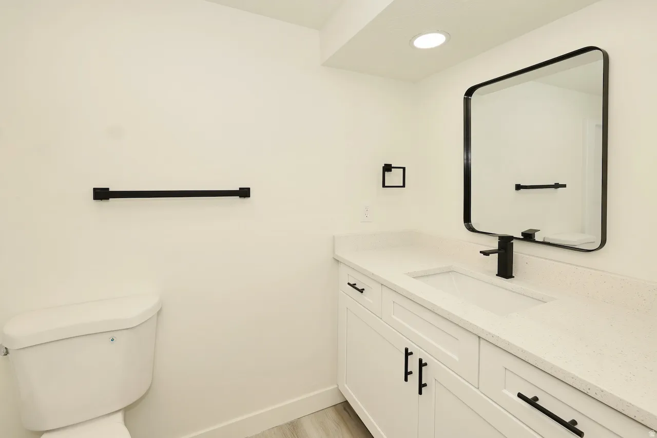 Bathroom featuring a contemporary vanity with white shaker-style cabinetry, a built-in rectangular sink, and a light-toned countertop