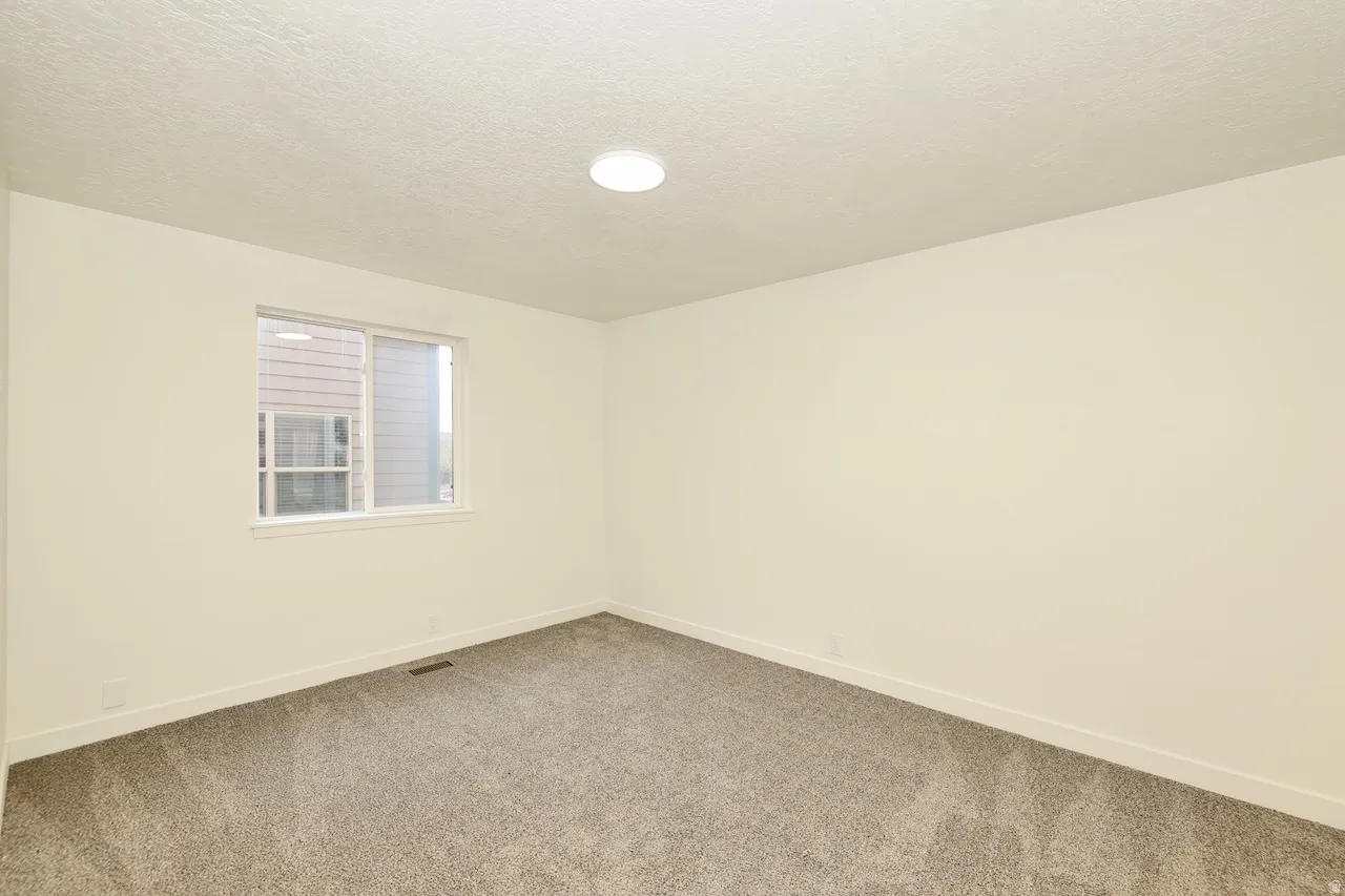 Neutral tone wall finishes with crisp white trim, plush gray carpeting, and a flush mount ceiling light fixture