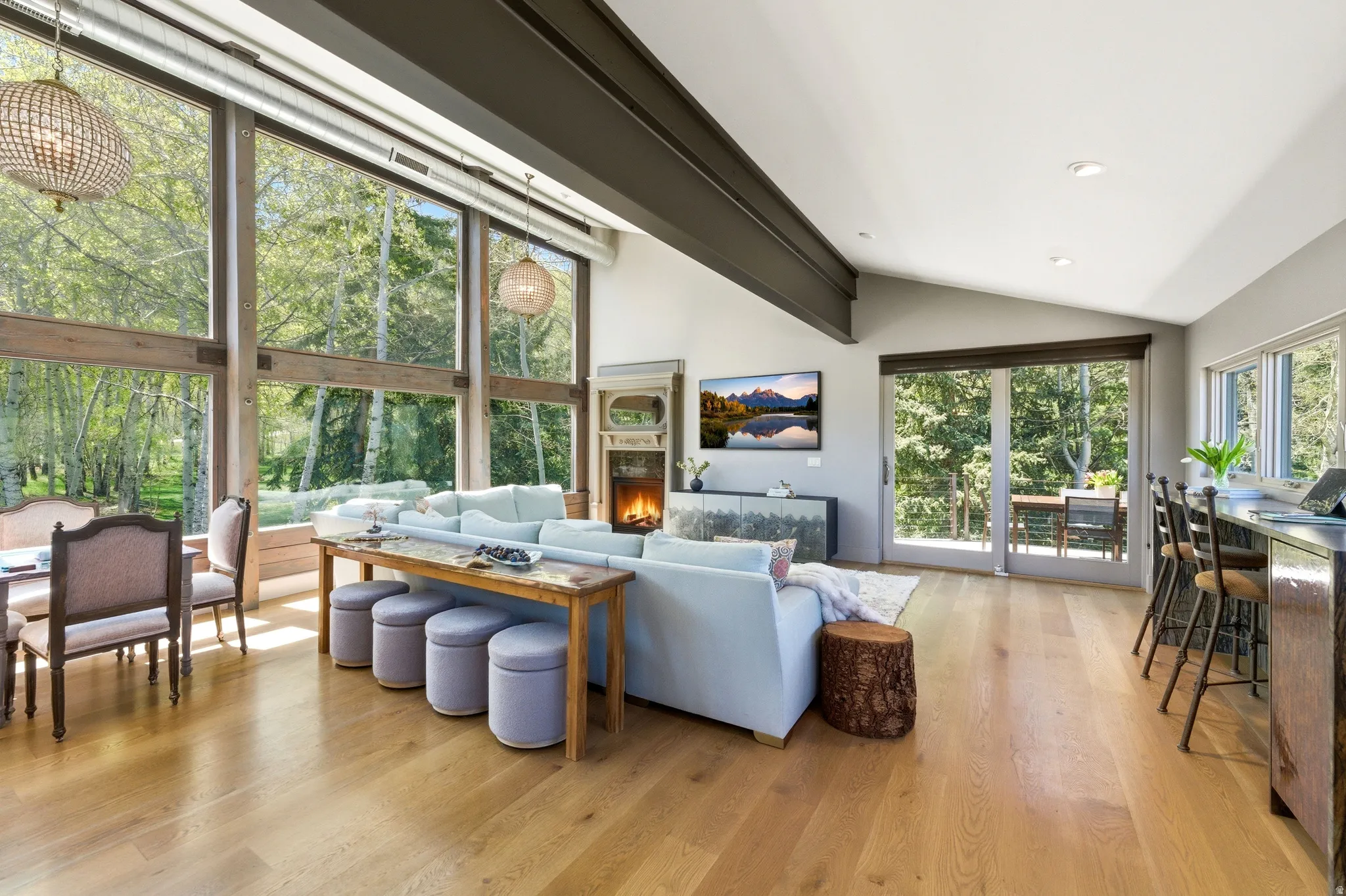 Open-concept living space featuring high ceilings, wood-finish flooring, and a stone fireplace
