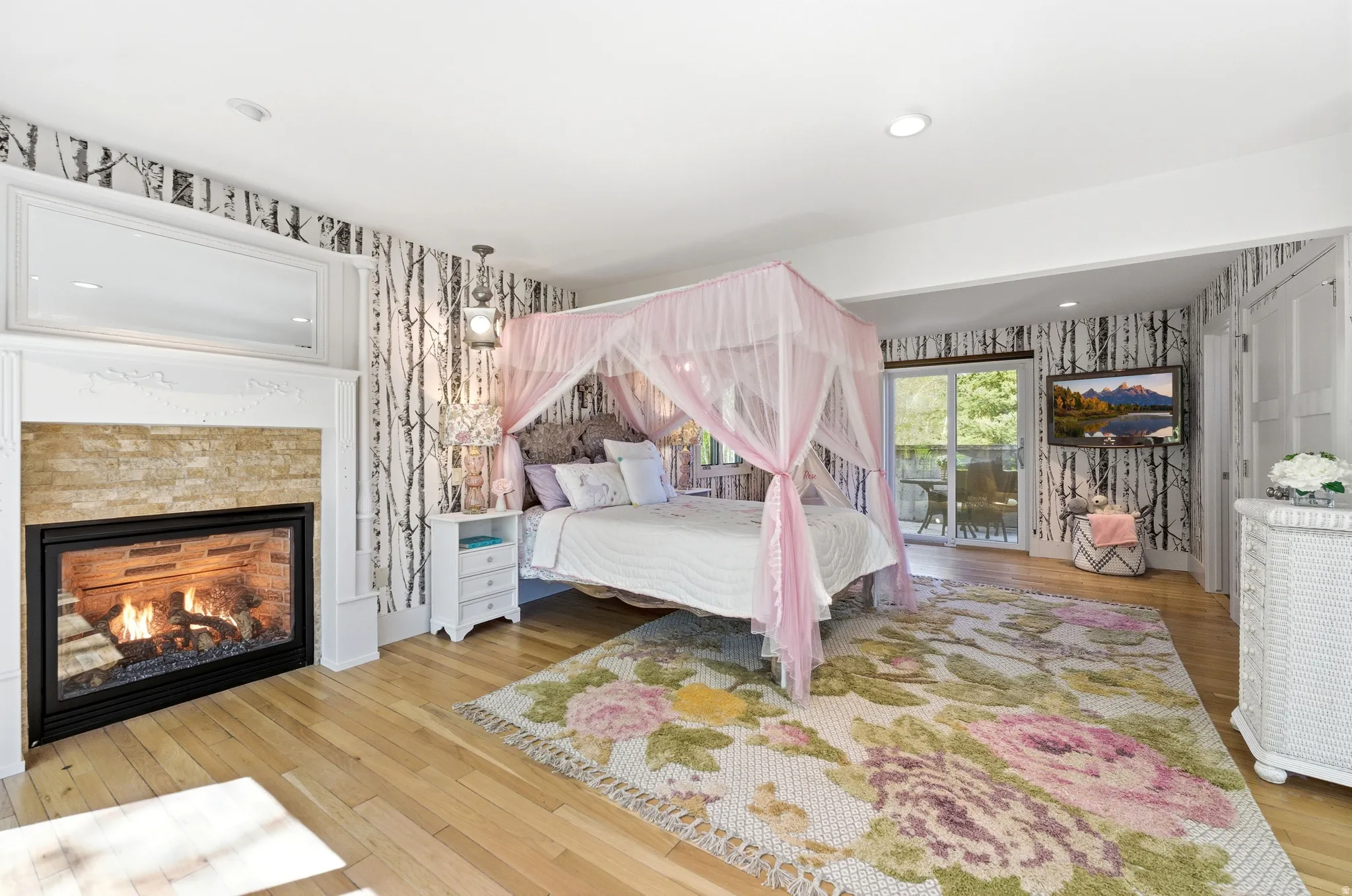 Hardwood flooring paired with a stone-clad fireplace and white mantel