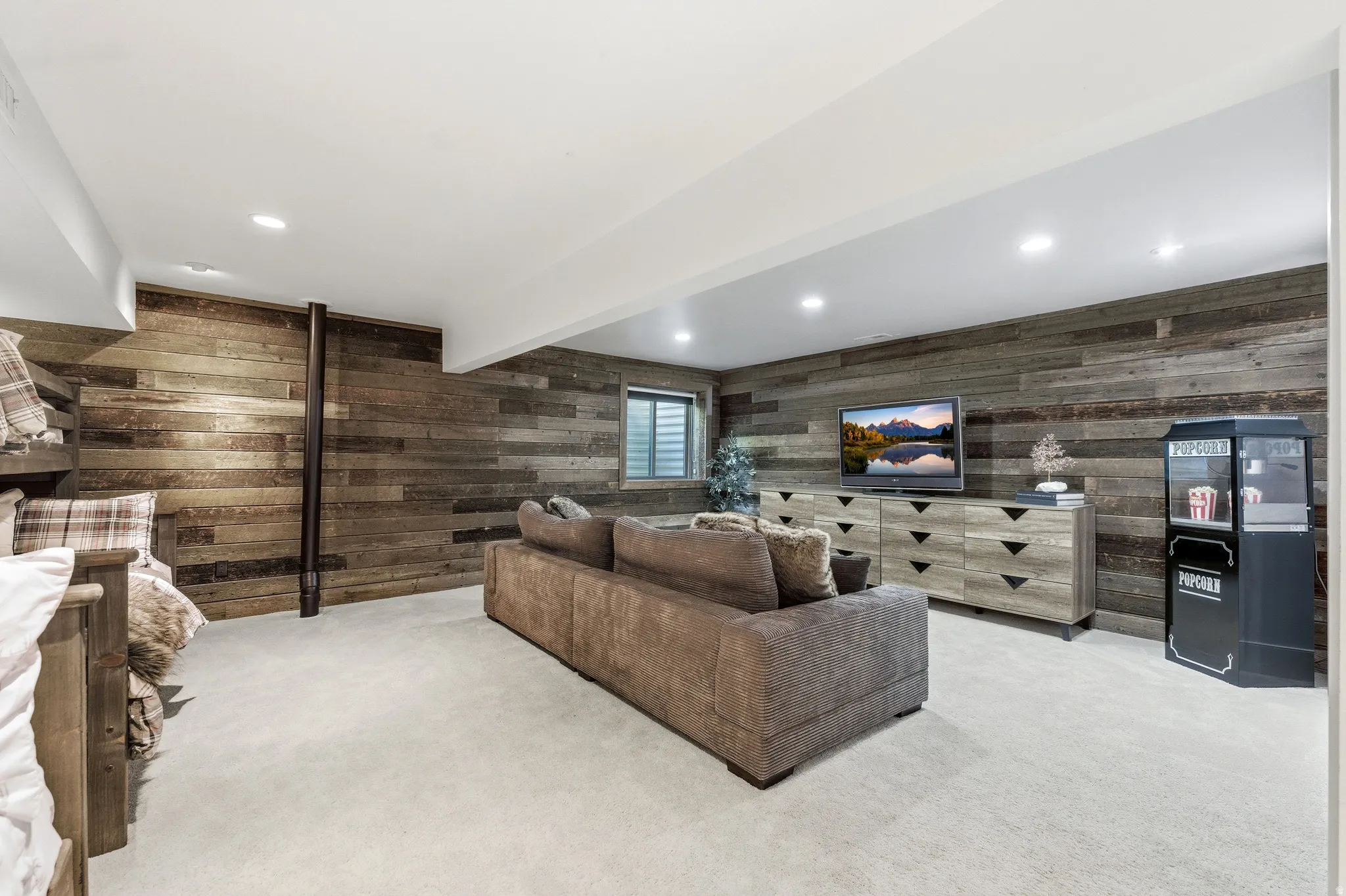 Spacious entertainment area featuring wood-plank accent walls, recessed lighting, and soft carpet flooring