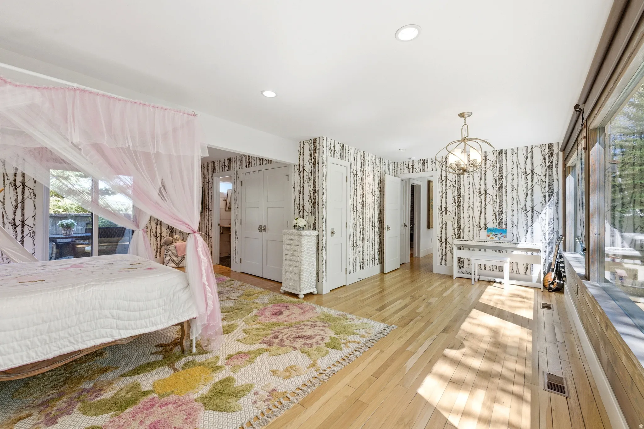 Spacious room featuring wood-finish flooring, recessed lighting, and a contemporary chandelier
