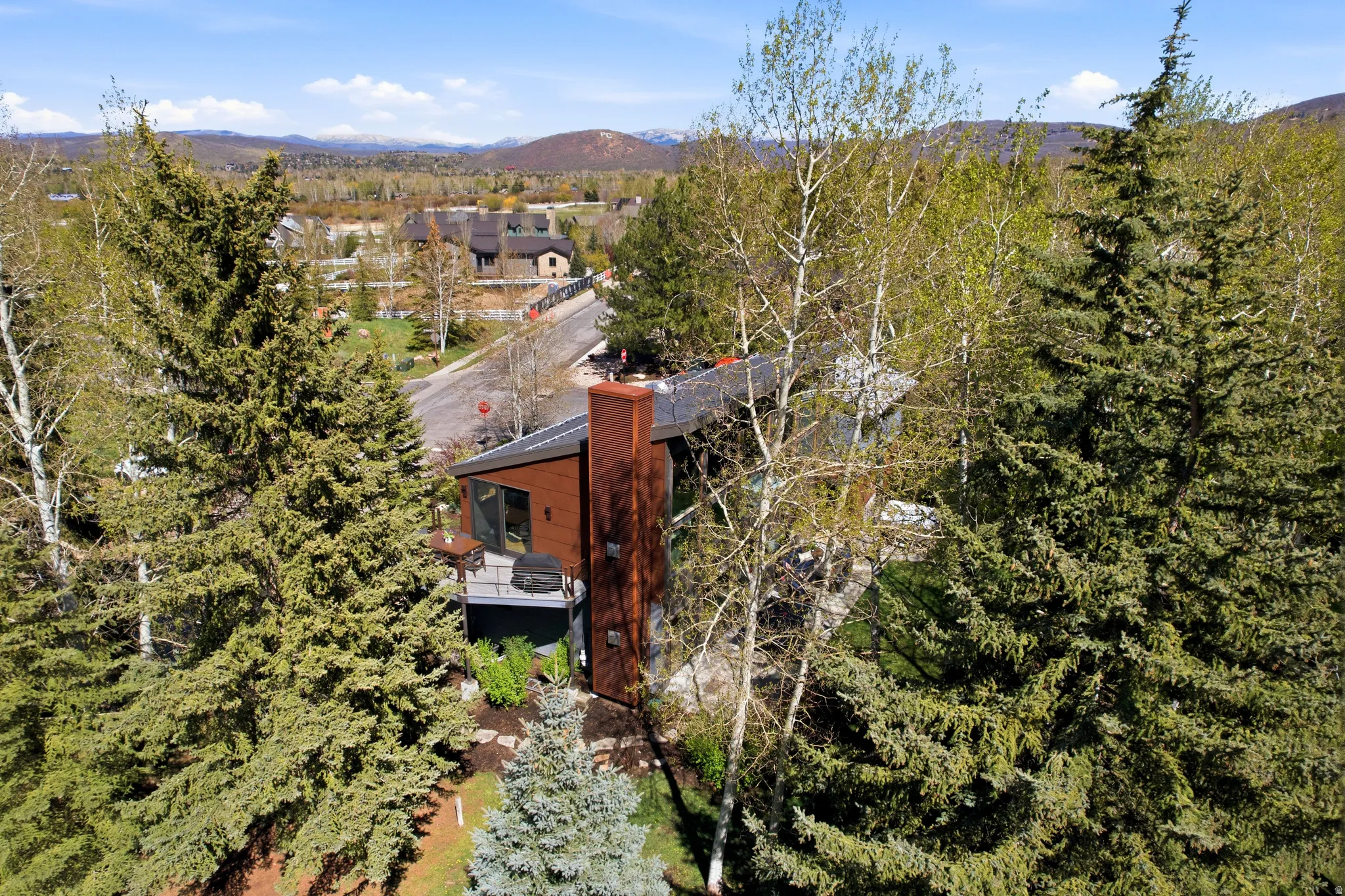 Multi-story exterior featuring a prominent rust-colored chimney, dark-toned siding, and a sloped roofline