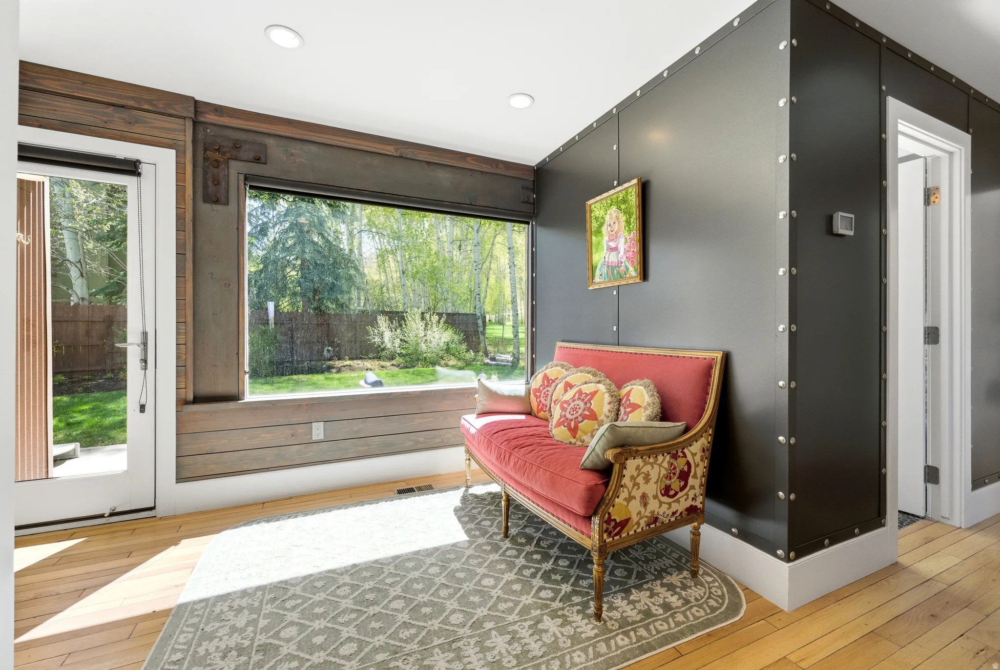 Hardwood flooring complements a spacious picture window with a wood-clad frame