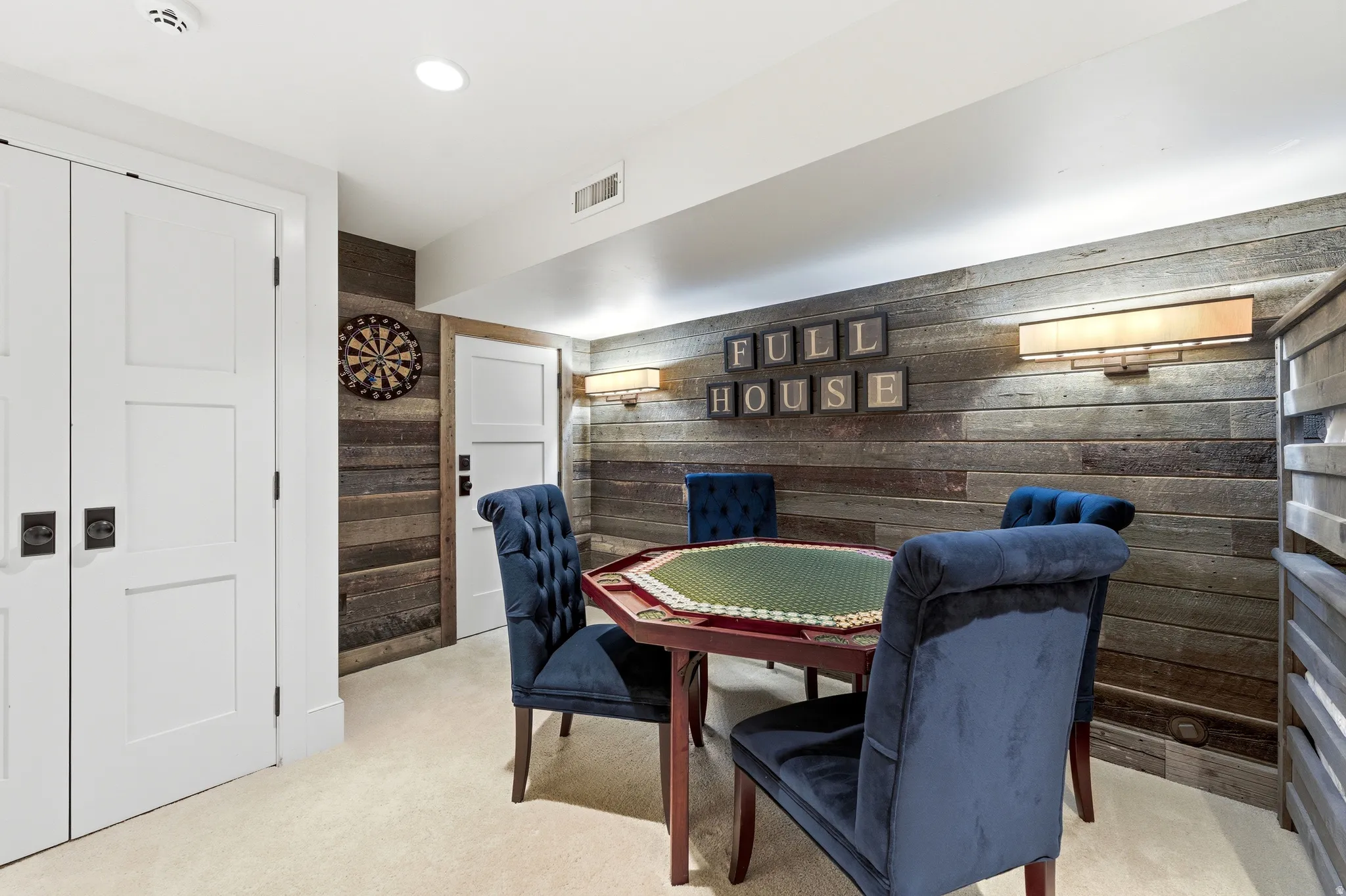 Reclaimed wood accent wall featuring sconce lighting, recessed ceiling lights, and light-colored carpeting