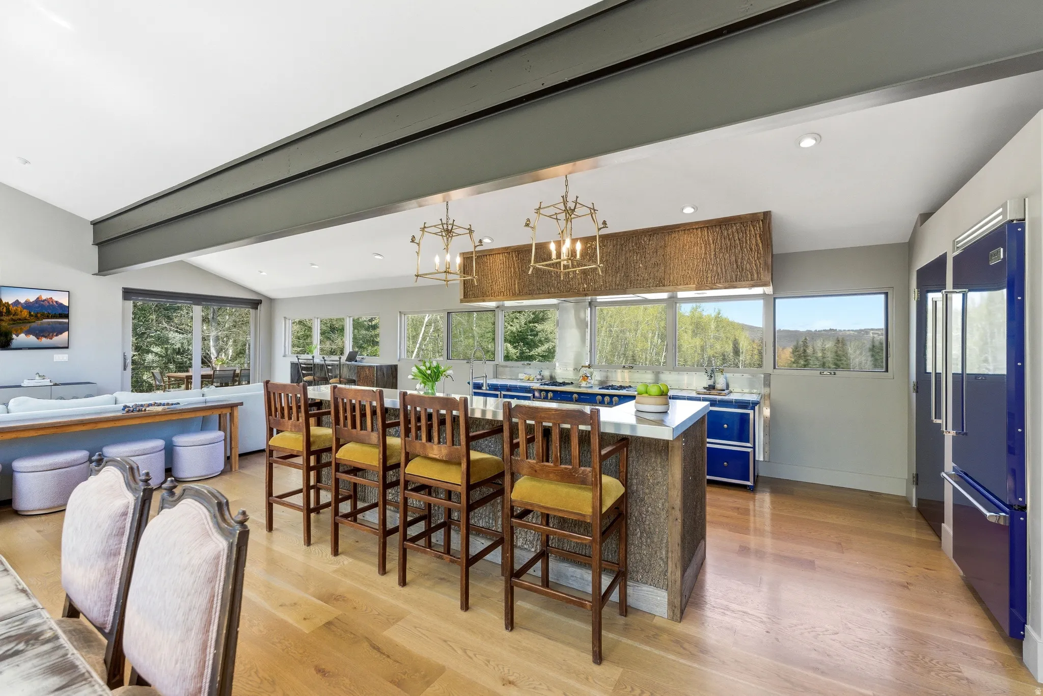 Open-concept kitchen and living area featuring high ceilings, wood-finish flooring, and expansive windows