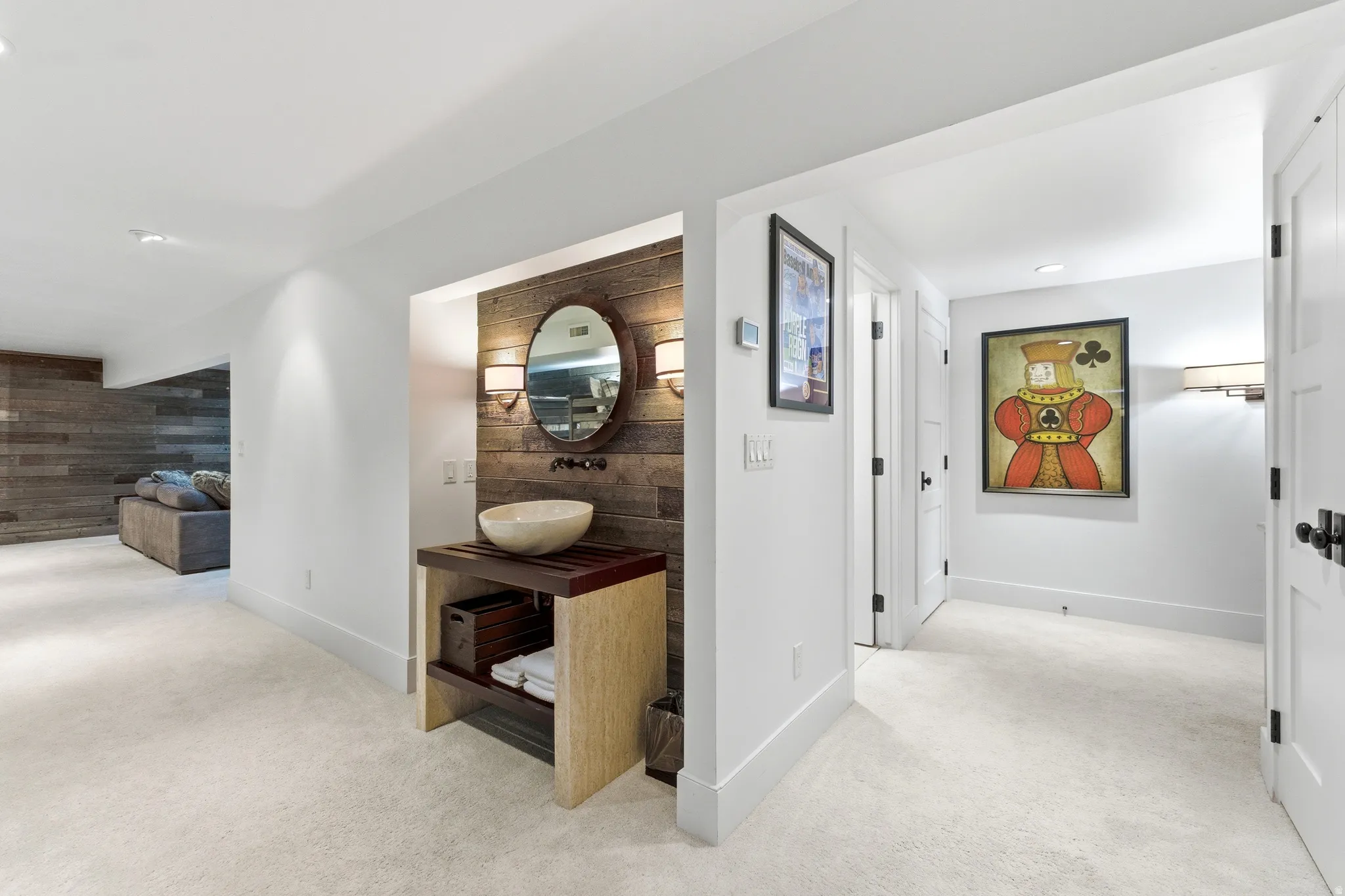 Powder room featuring a rustic wood-plank accent wall, vessel sink, and round mirror with two sconces