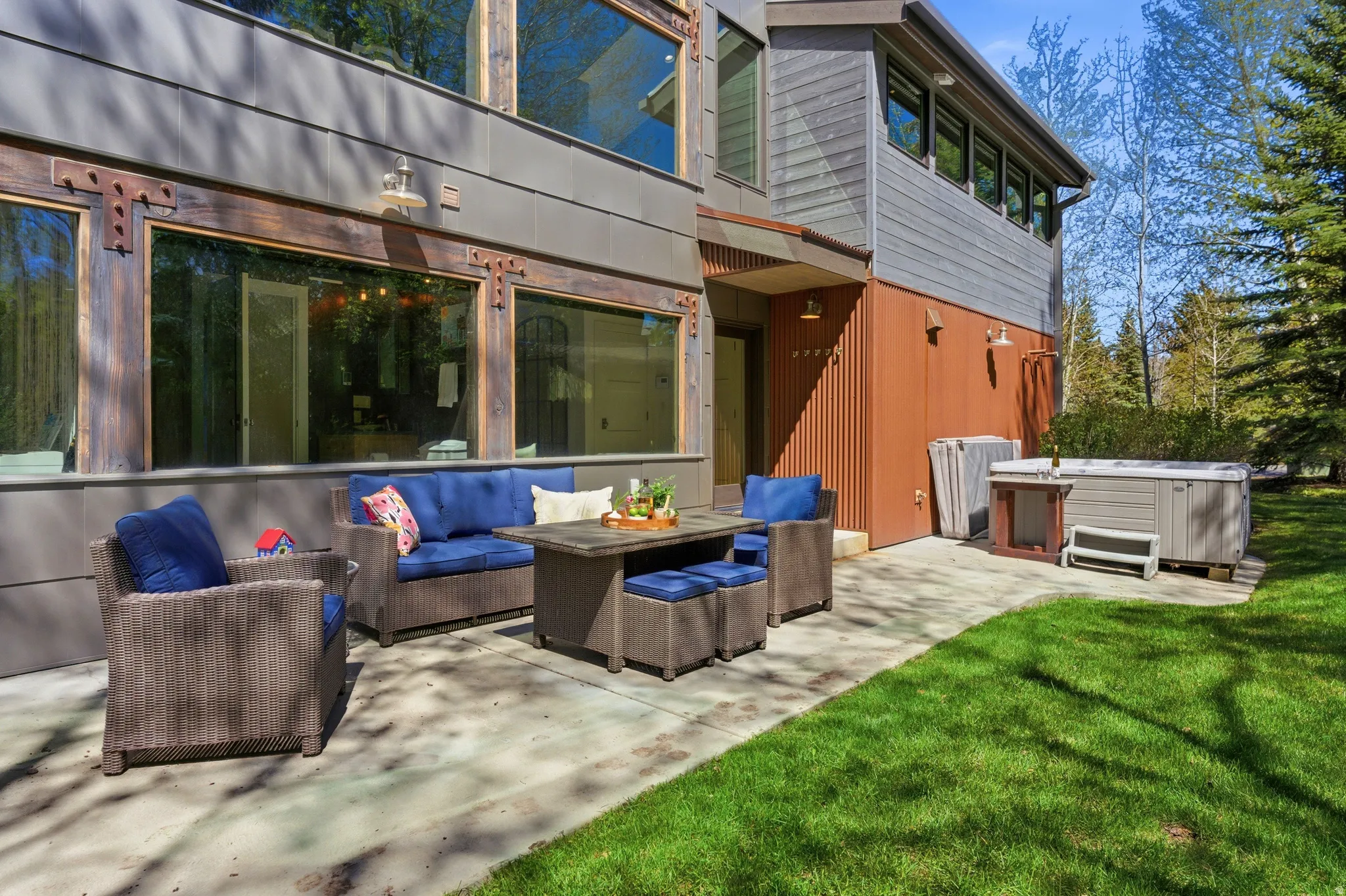 Exterior patio featuring a concrete surface, surrounding green lawn, and a hot tub