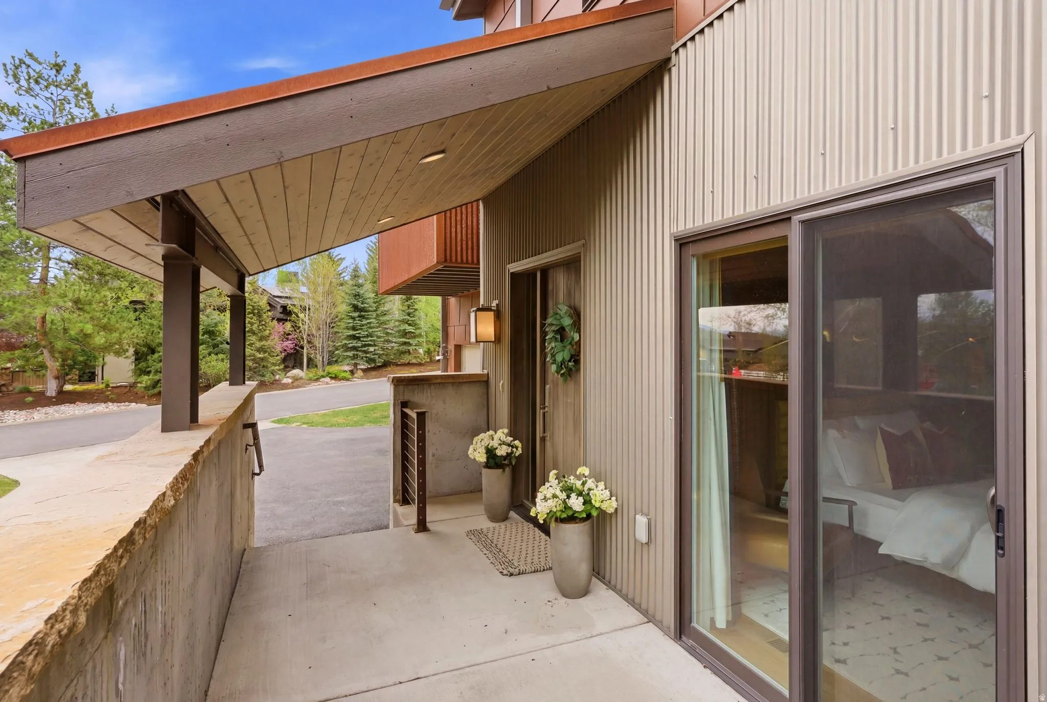 Covered entryway featuring a corrugated metal exterior, concrete slab flooring, and a stone-capped concrete retaining wall