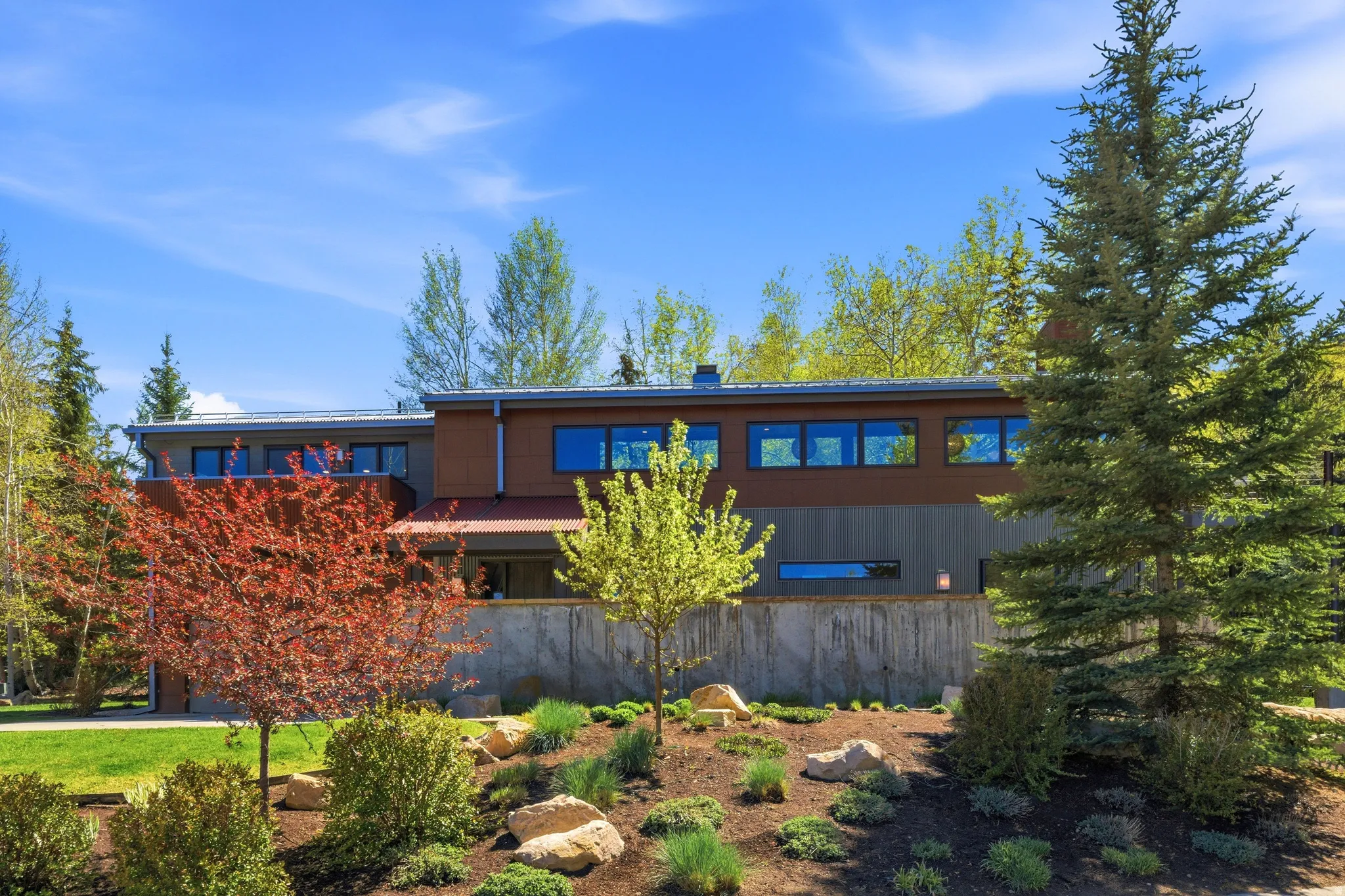 Modern architectural structure featuring multi-level design, a concrete retaining wall, and horizontal siding