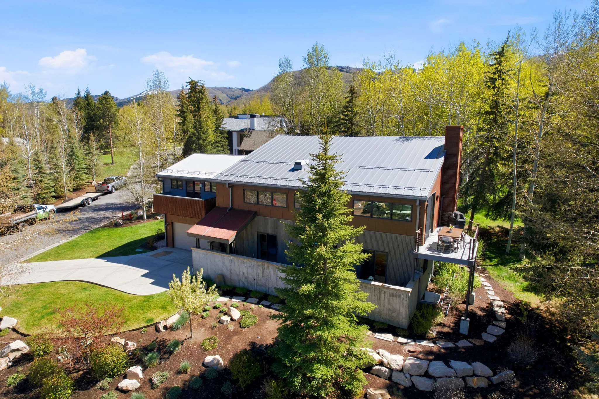 Contemporary residence featuring a metal roof, a prominent chimney, and a concrete driveway
