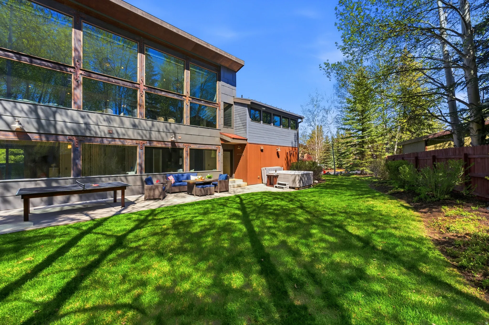 Rear exterior showcasing a multi-level design with extensive floor-to-ceiling windows, a concrete patio, and a hot tub on a concrete pad