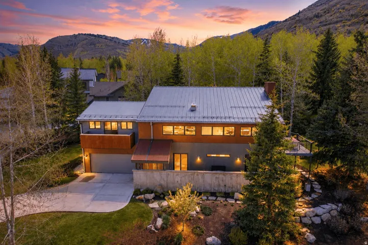 Modern mountain residence featuring a metal roof and a blend of wood-finish and gray siding