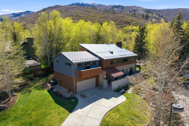 Contemporary architectural design featuring a metal roof, wood siding, and stone accents