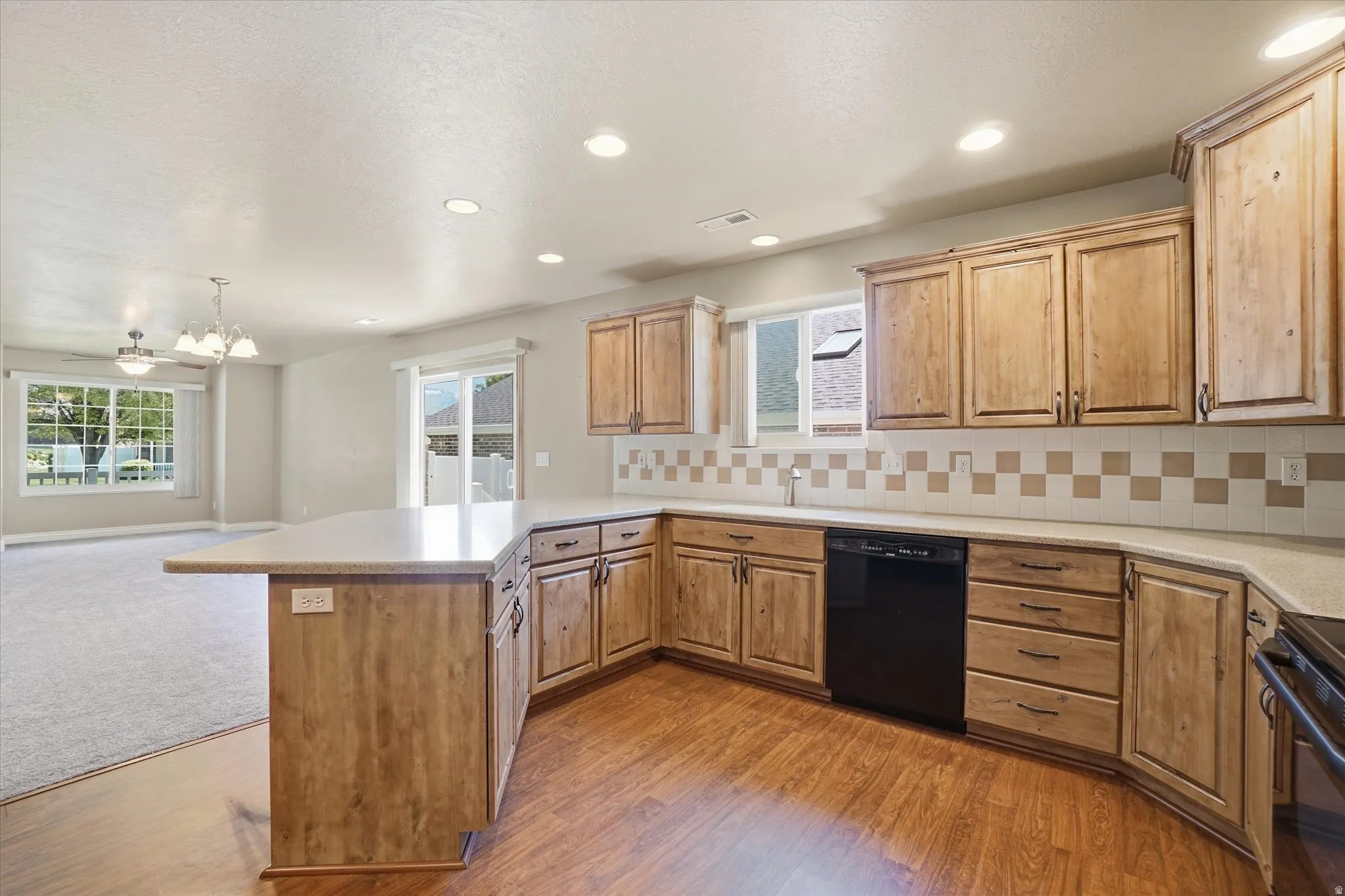 Kitchen featuring L-shaped counter seating, light wood-finish cabinetry, black appliances, and recessed lighting