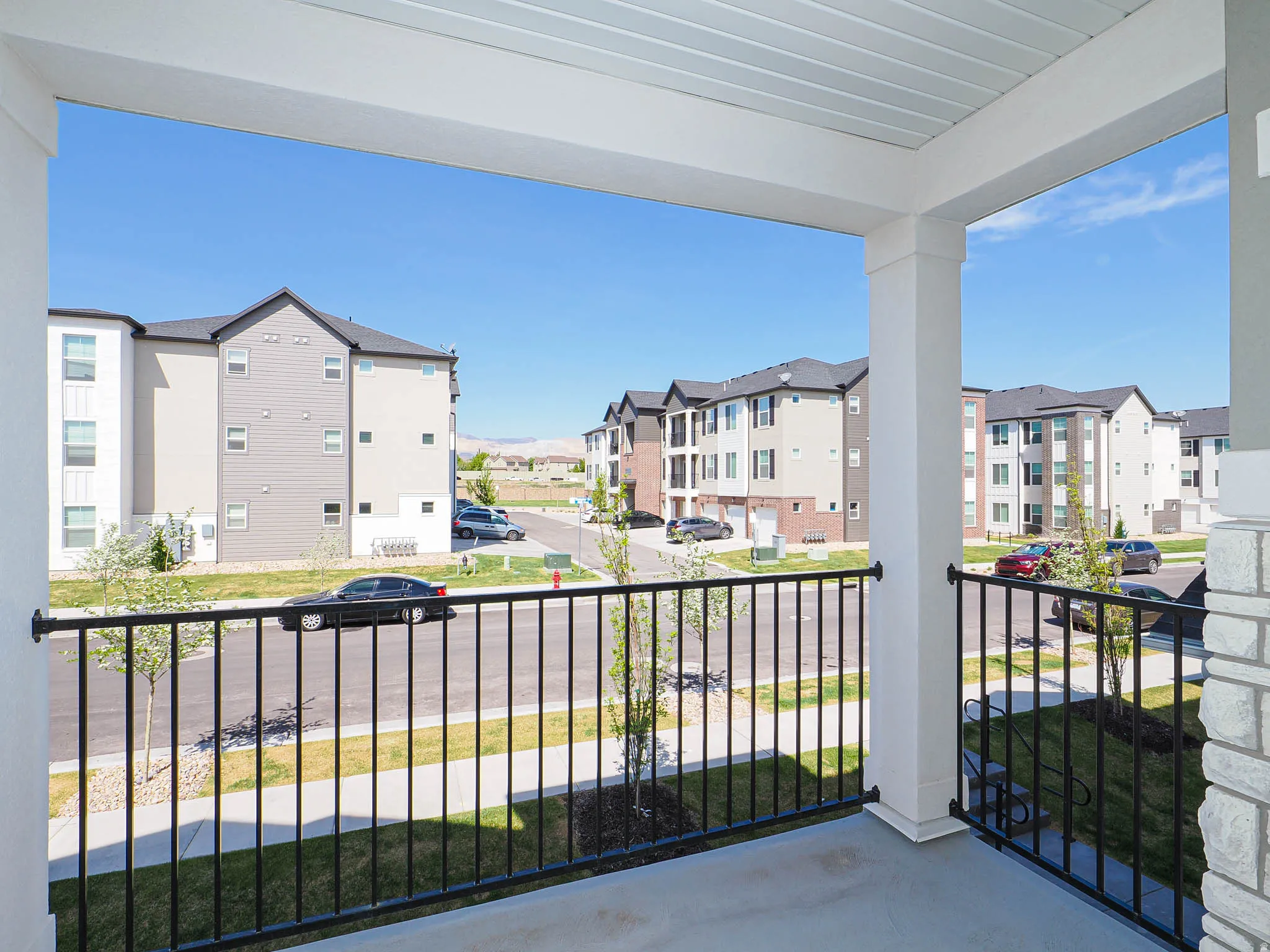 Covered balcony with black metal railings, white columns, and a concrete floor