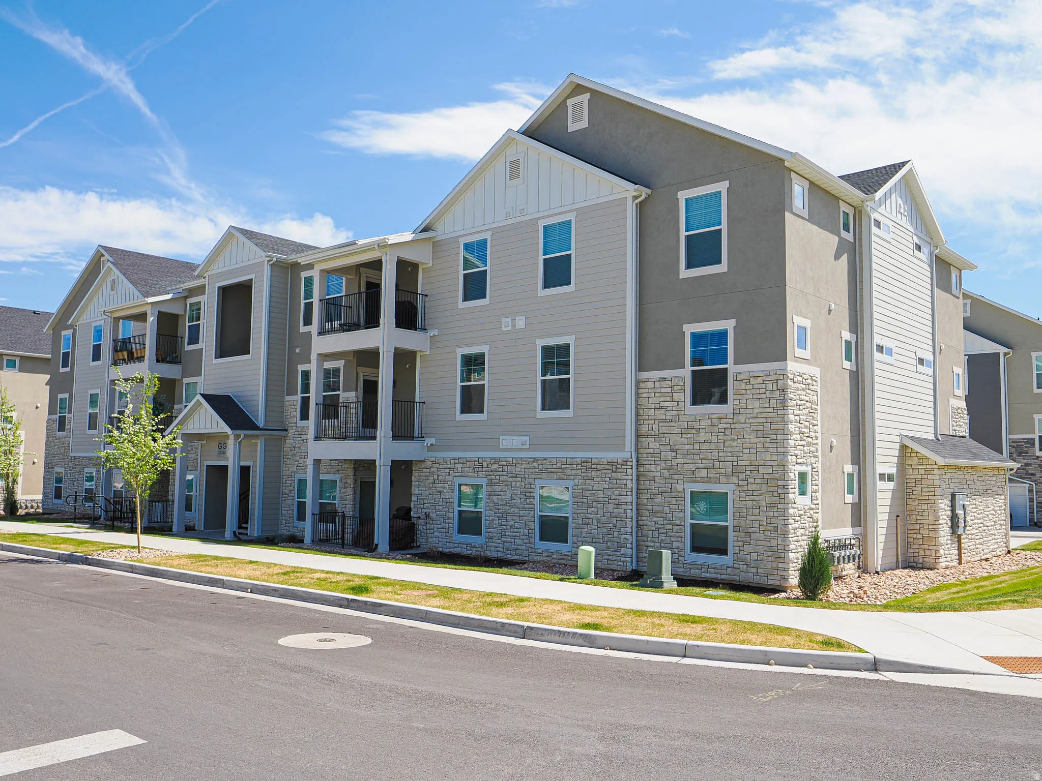 Multi-story building featuring a facade of stone veneer, stucco, and horizontal siding