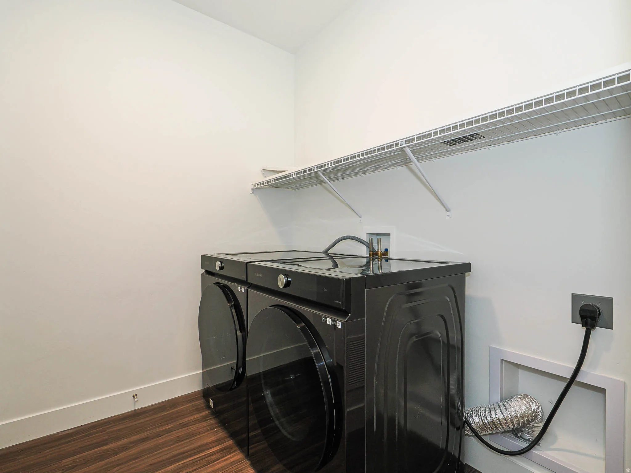 Dedicated laundry area featuring wood-finish flooring and a white wire shelf