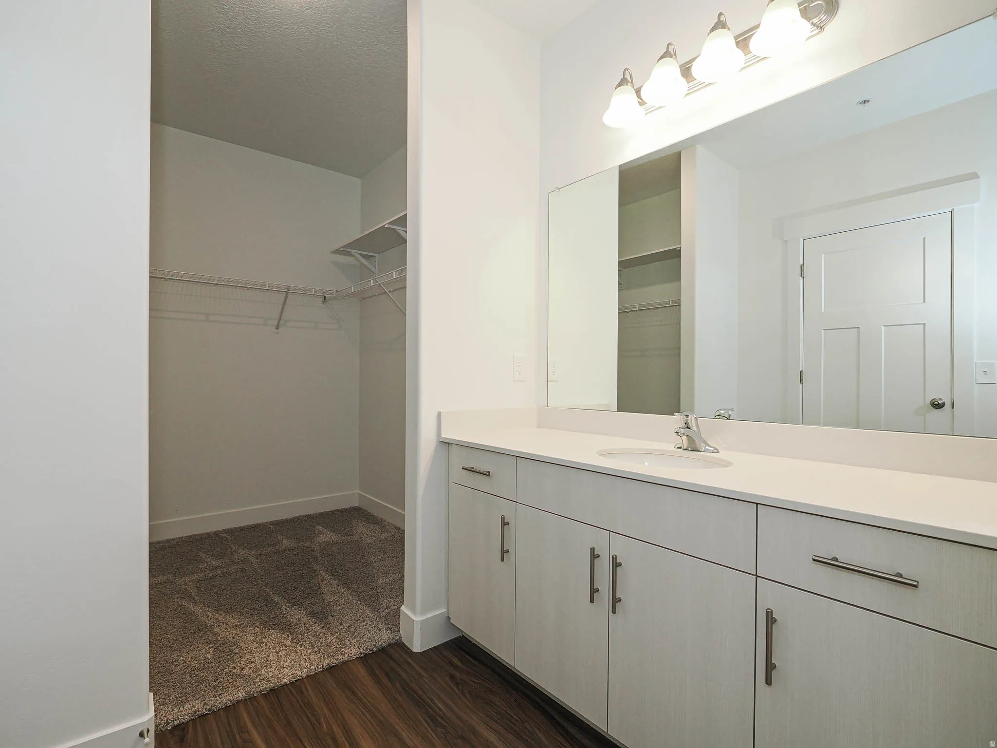 Vanity area featuring a single basin, light-toned countertop, and extensive cabinetry with modern hardware