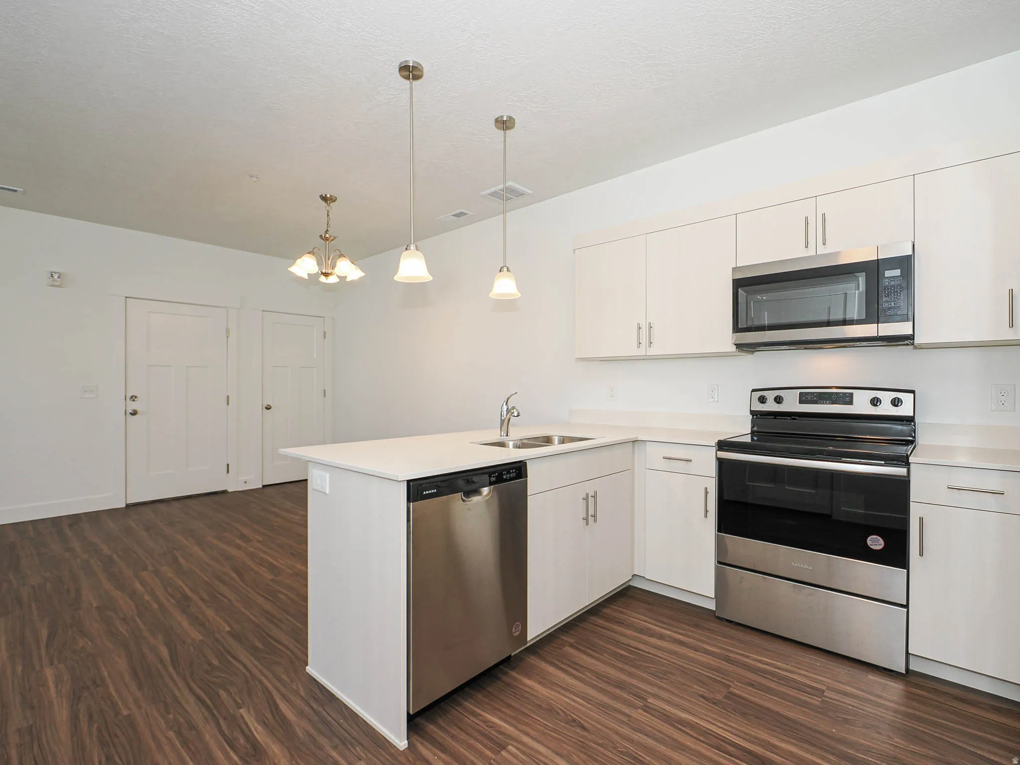 Modern kitchen featuring white cabinetry, light countertops, and stainless steel appliances including a range, microwave, and dishwasher
