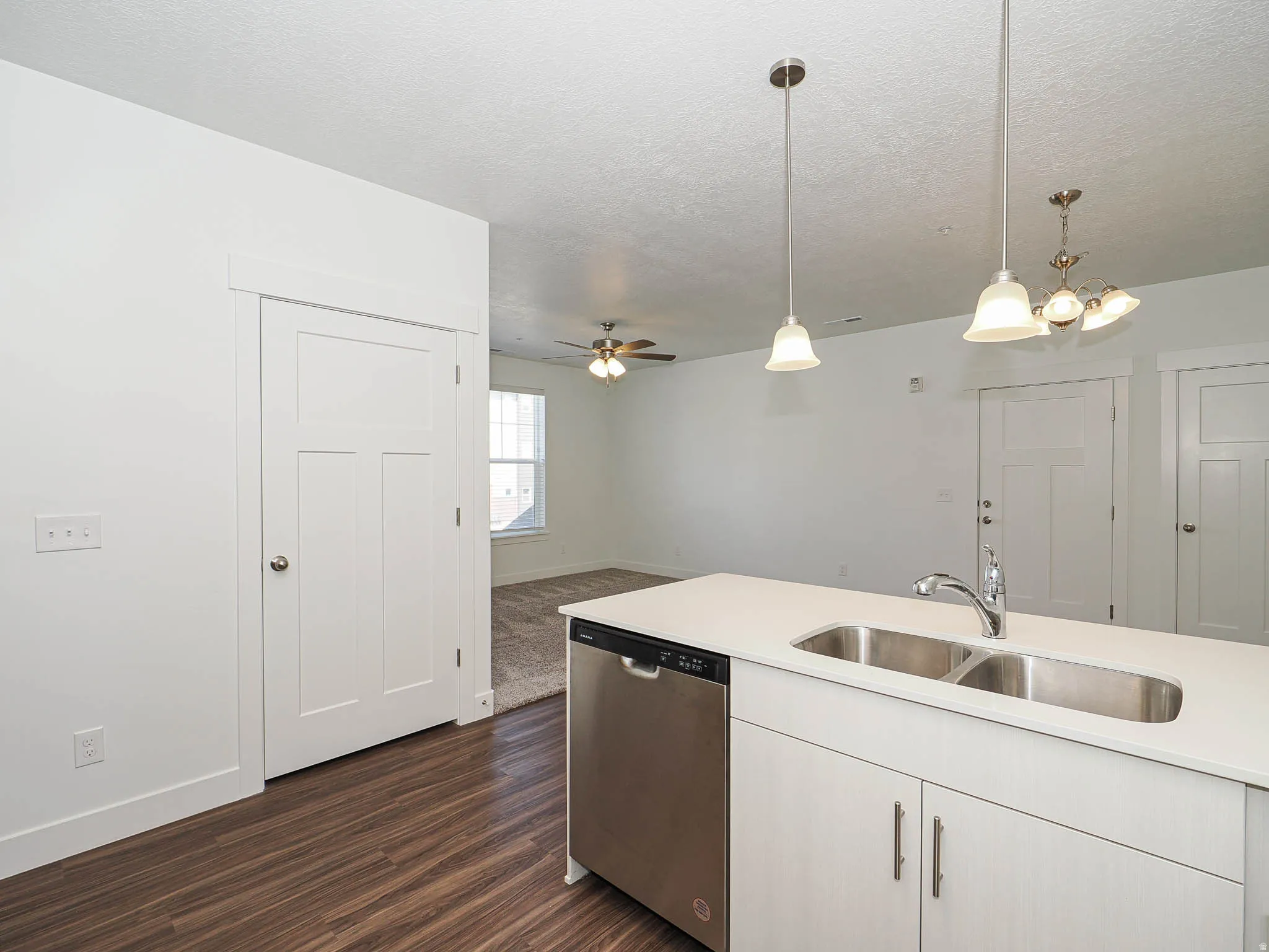 Kitchen island featuring a double basin stainless steel sink, chrome faucet, and integrated stainless steel dishwasher