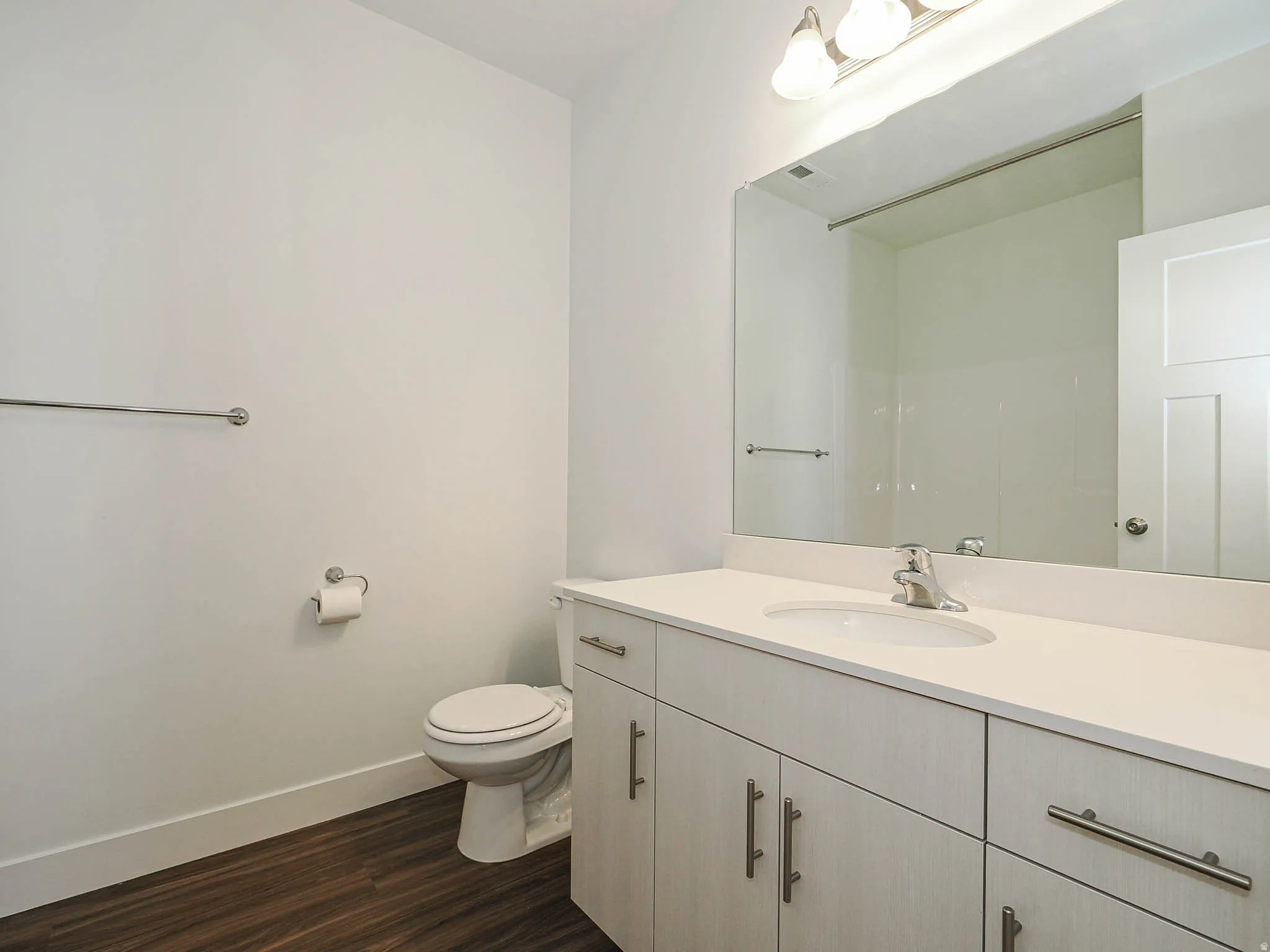 Bathroom featuring a light-toned vanity with an integrated sink, polished chrome faucet, and coordinating hardware