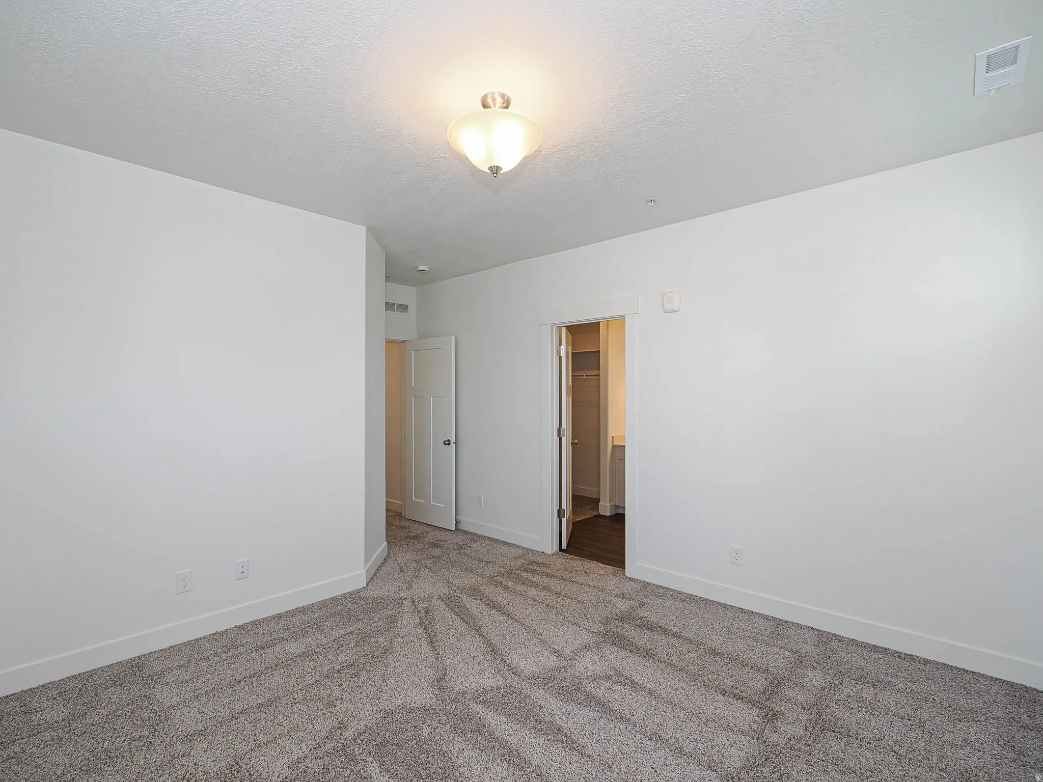 Spacious room featuring neutral carpeting, white walls, and a semi-flush mount ceiling light fixture