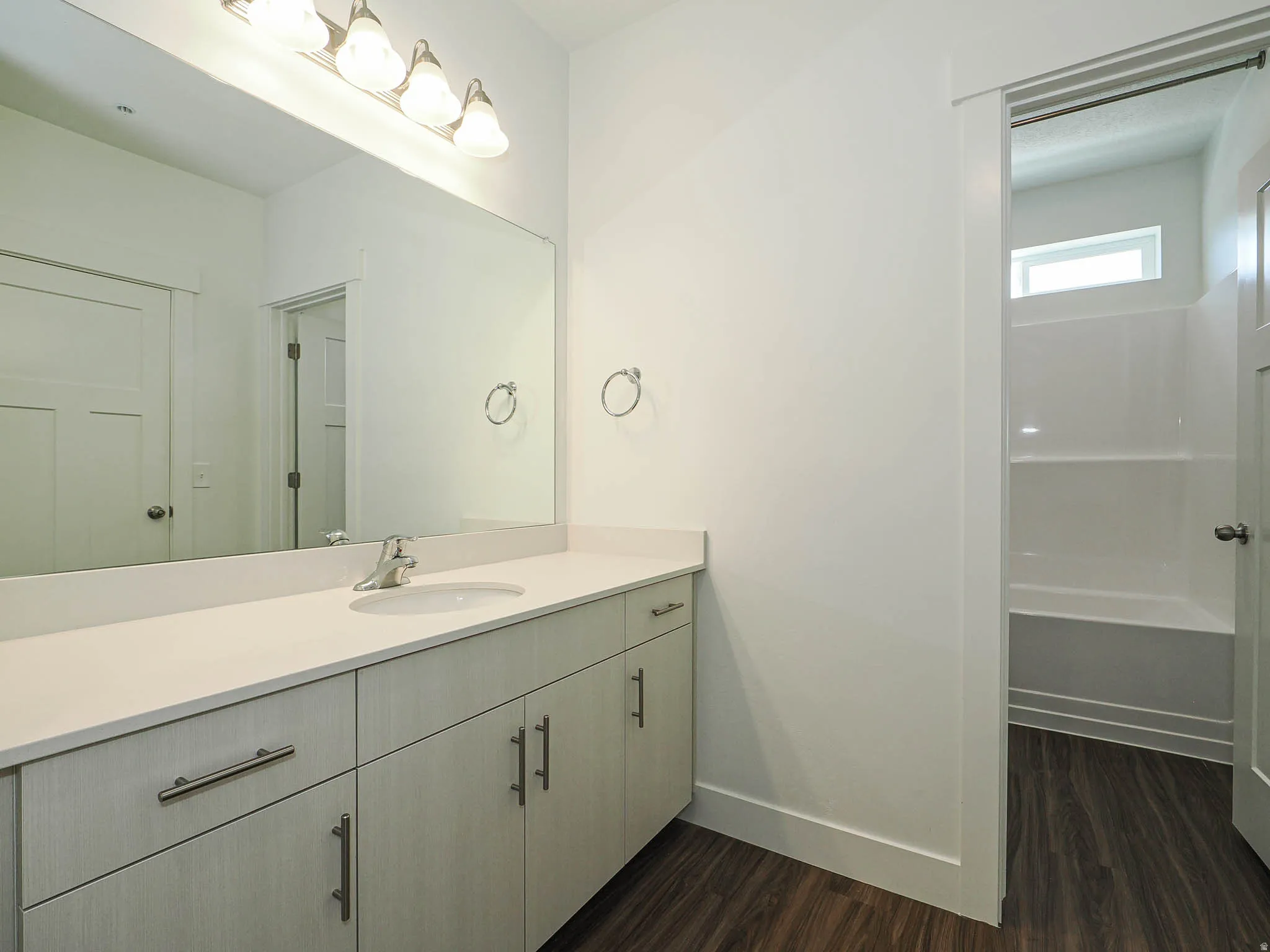 Bathroom vanity featuring a light-toned countertop, integrated sink, and brushed nickel faucet