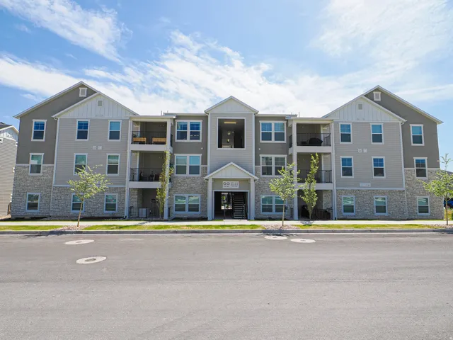 Modern multi-story building featuring light gray siding and stone veneer accents