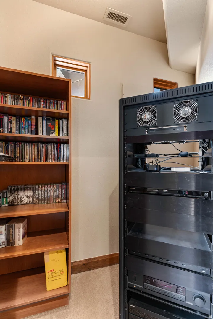 Built-in shelving unit with media storage, high ceilings with recessed windows, and a dedicated equipment rack