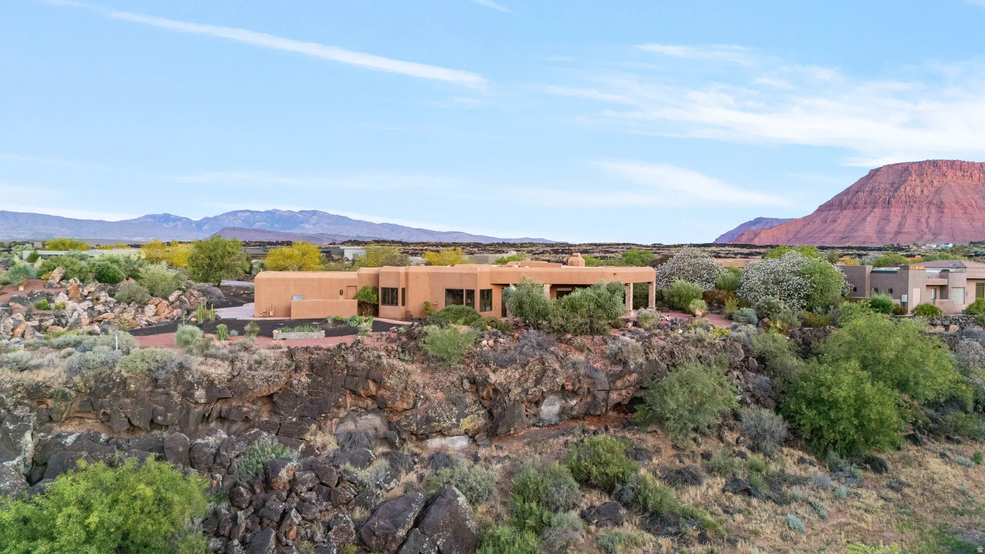 Terracotta-colored stucco exterior with a flat roofline, integrated landscaping, and large windows