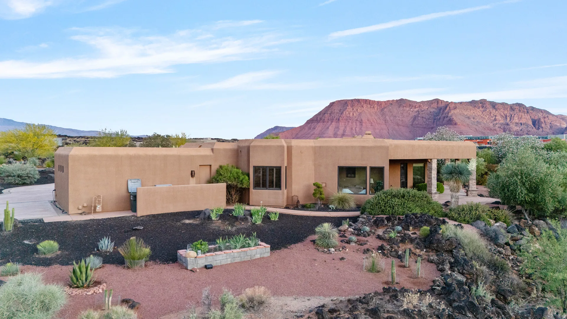 Southwestern-style residence featuring a stucco exterior, integrated covered patio, desert landscaping, and a prominent mountain backdrop